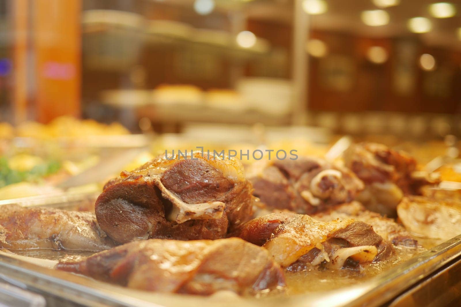 Succulent meat options are served at a bustling restaurant buffet.