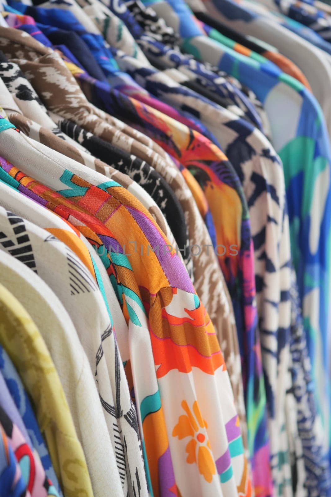 Brightly colored shirts are neatly organized on hangers in a shop setting.