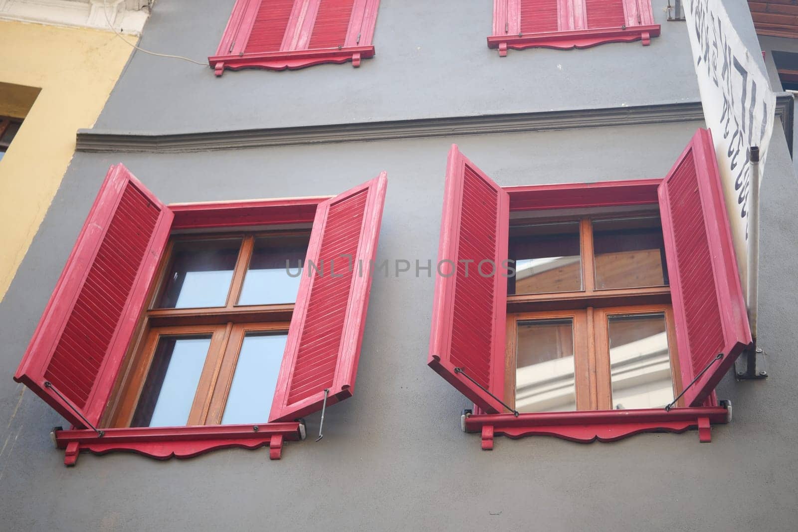 Colorful red shutters open on wooden windows of a charming building.