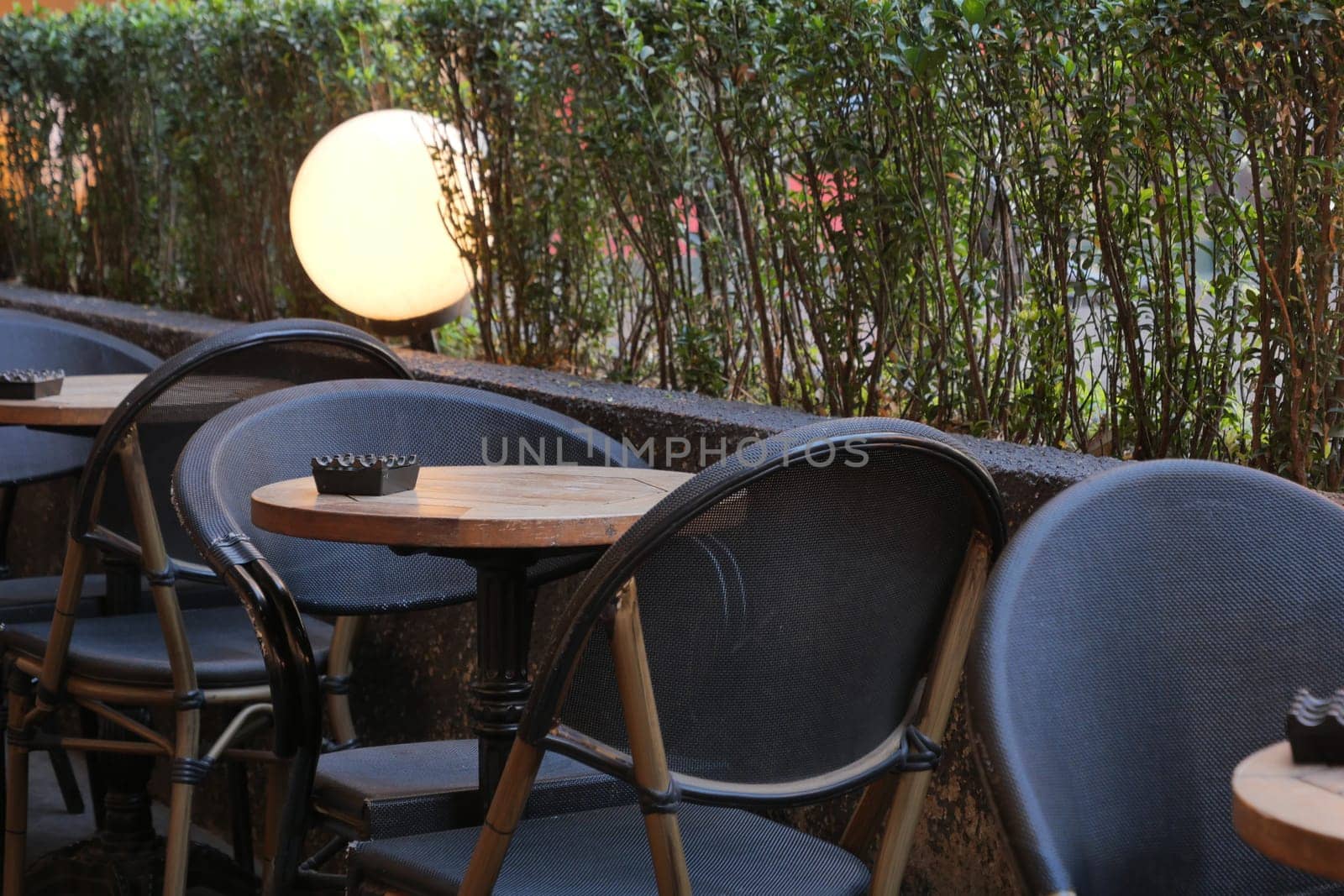 Several chairs and tables are arranged neatly outside a cafe at dusk.