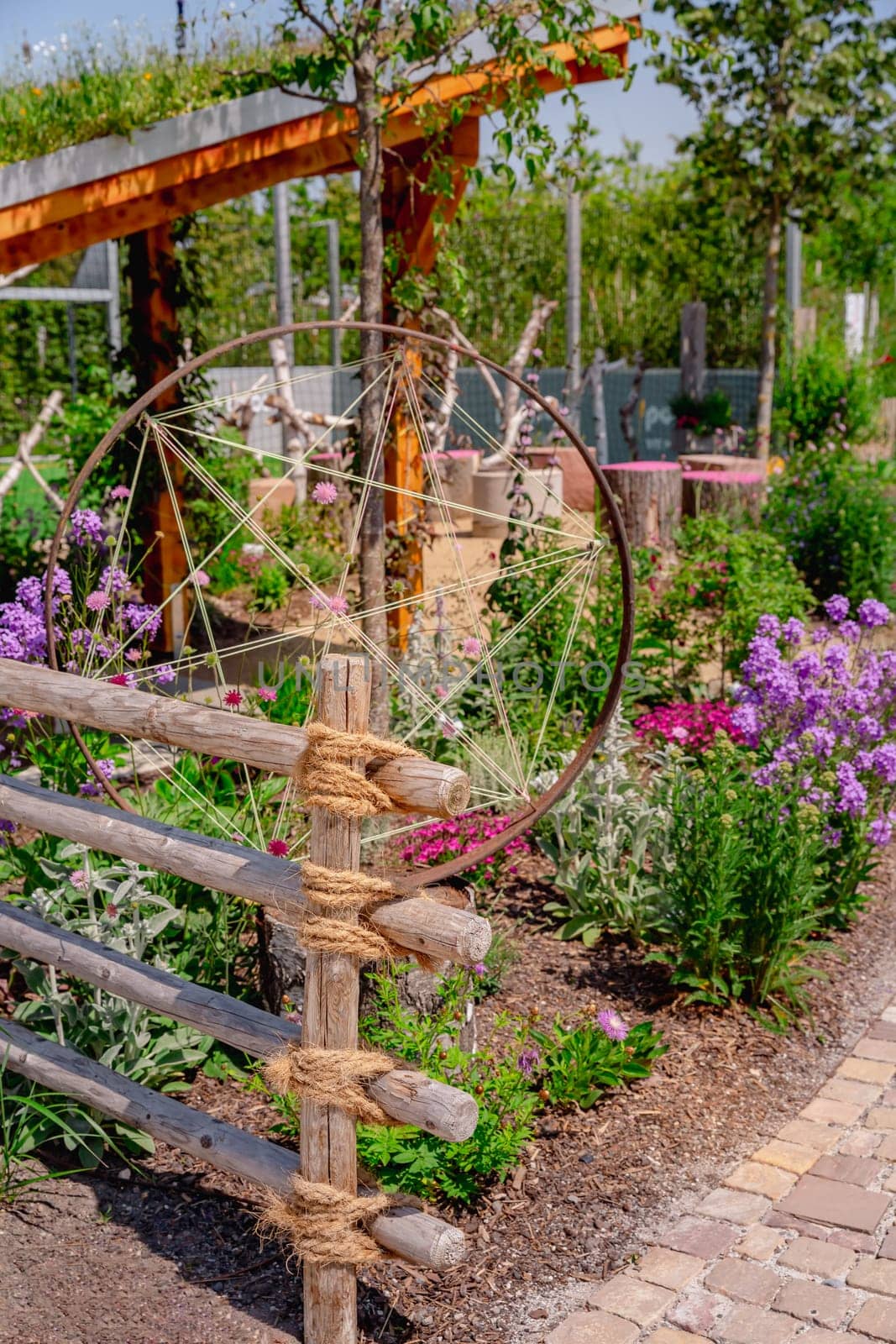 Detail of natural garden fence made of wooden posts and ropes with native plants and patio