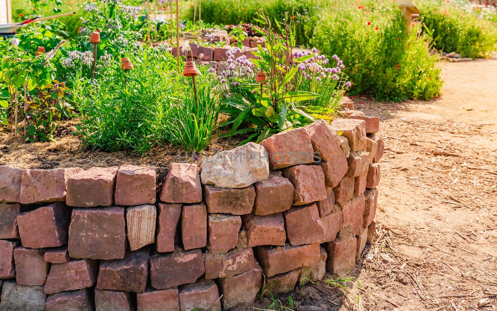 Herb spiral made of bricks for a small garden. Non-English translation: garlic, sorrel