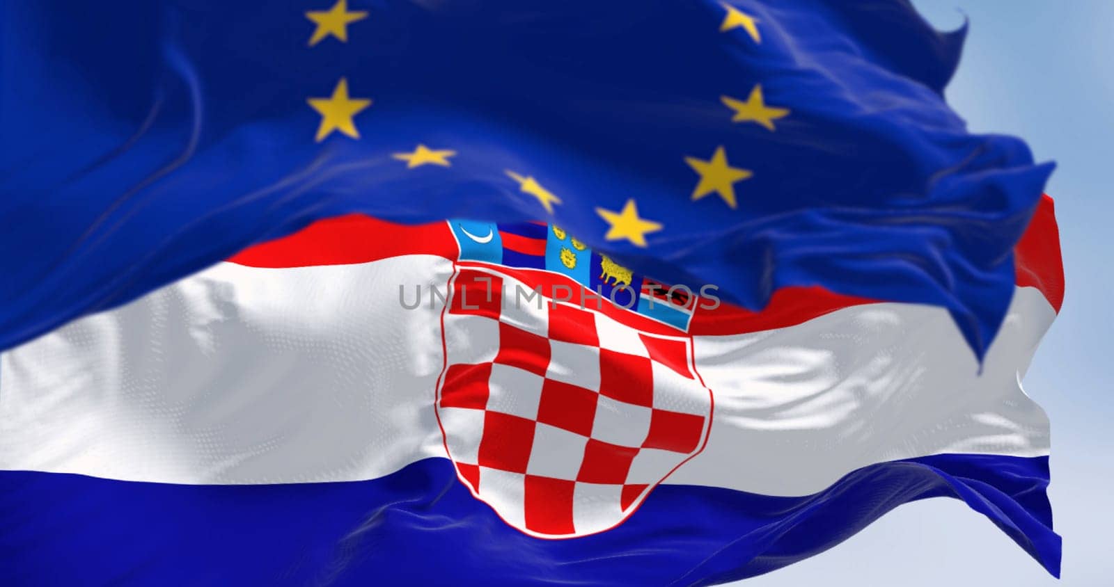 The flags of Croatia and the European Union fluttering together on a clear day. Croatia has been a member of the eurozone since January 1, 2023. 3D illustration render. Fluttering fabric