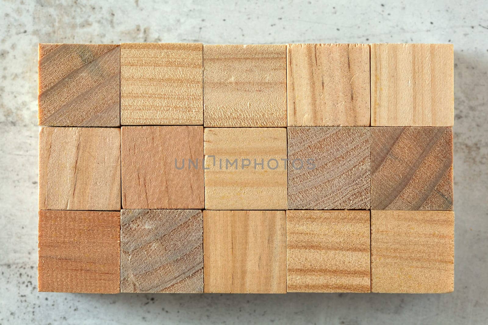 Top view - 15 small wooden cubes arranged to 3 x 5 grid, on concrete board. Letters can be added.