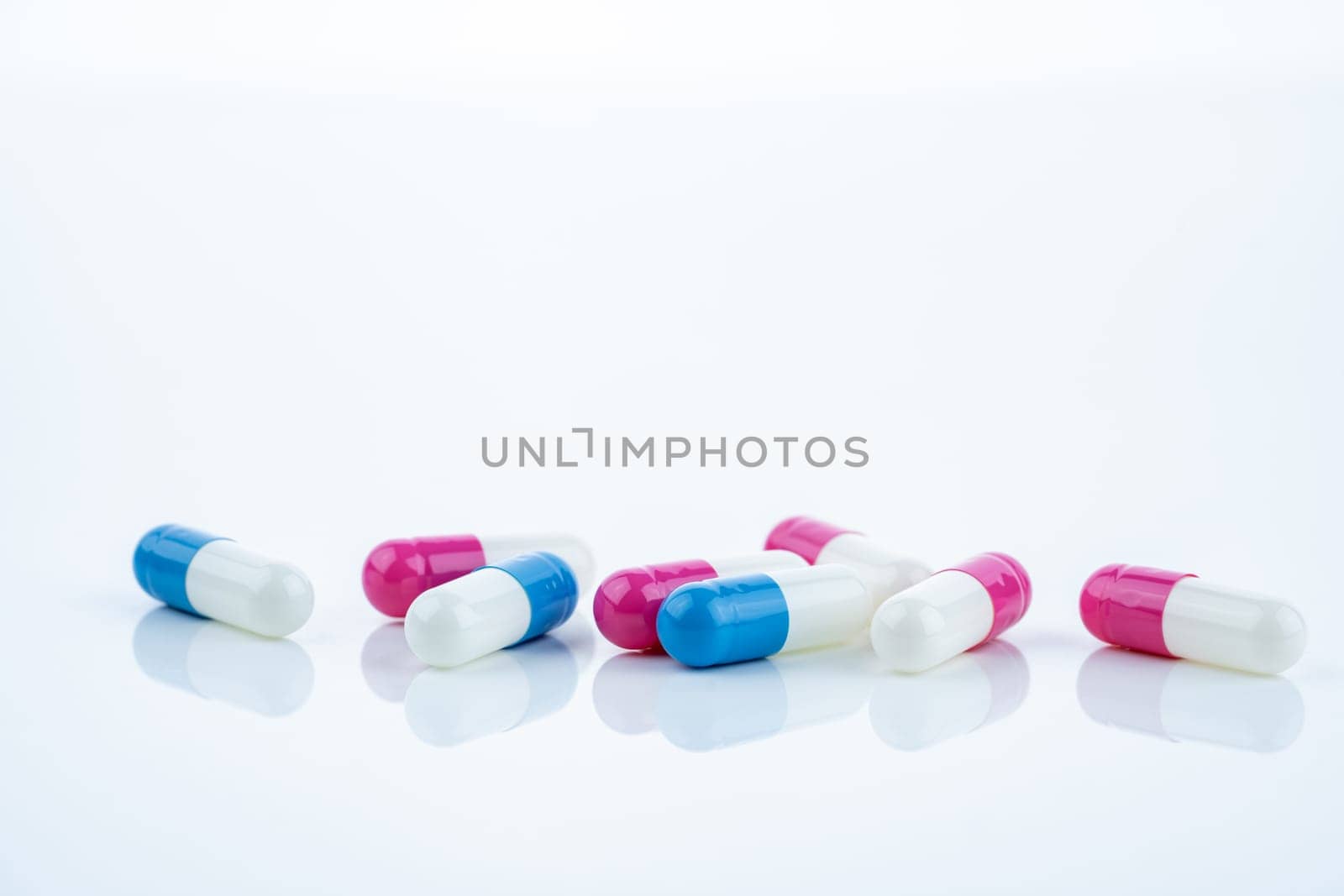 Blue and pink capsule pills spread on white background, showcasing pharmaceutical products, healthcare concepts, and the role of prescription medicine in advancing treatment and patient well-being.