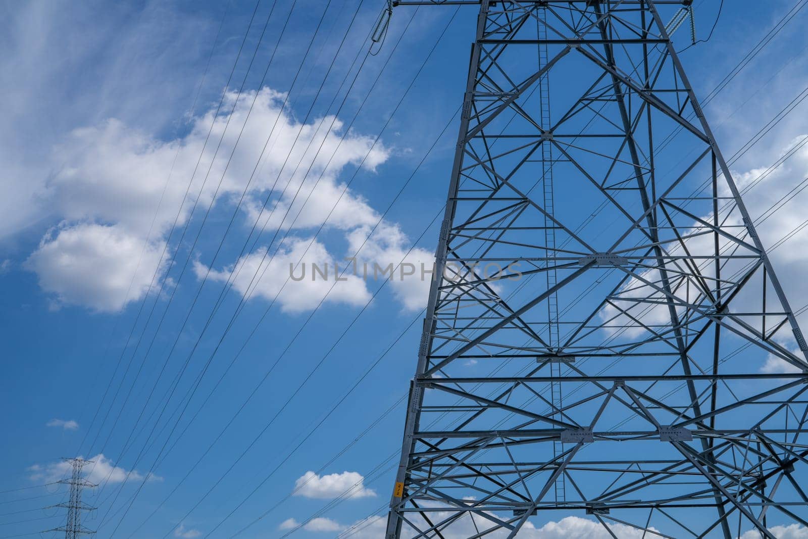 High voltage electric transmission tower with power lines against the sky, highlighting electricity supply, industrial infrastructure, energy distribution, and the challenges of the energy crisis.