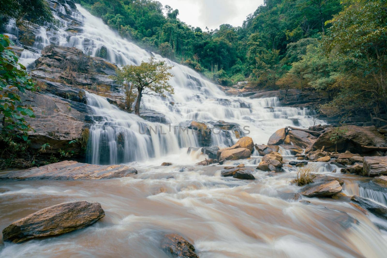 Beautiful waterfall with a lush green forest in the background. The water is flowing down the rocks and creating a beautiful scene. Sustainable waterfall in lush forest promoting water sustainability.