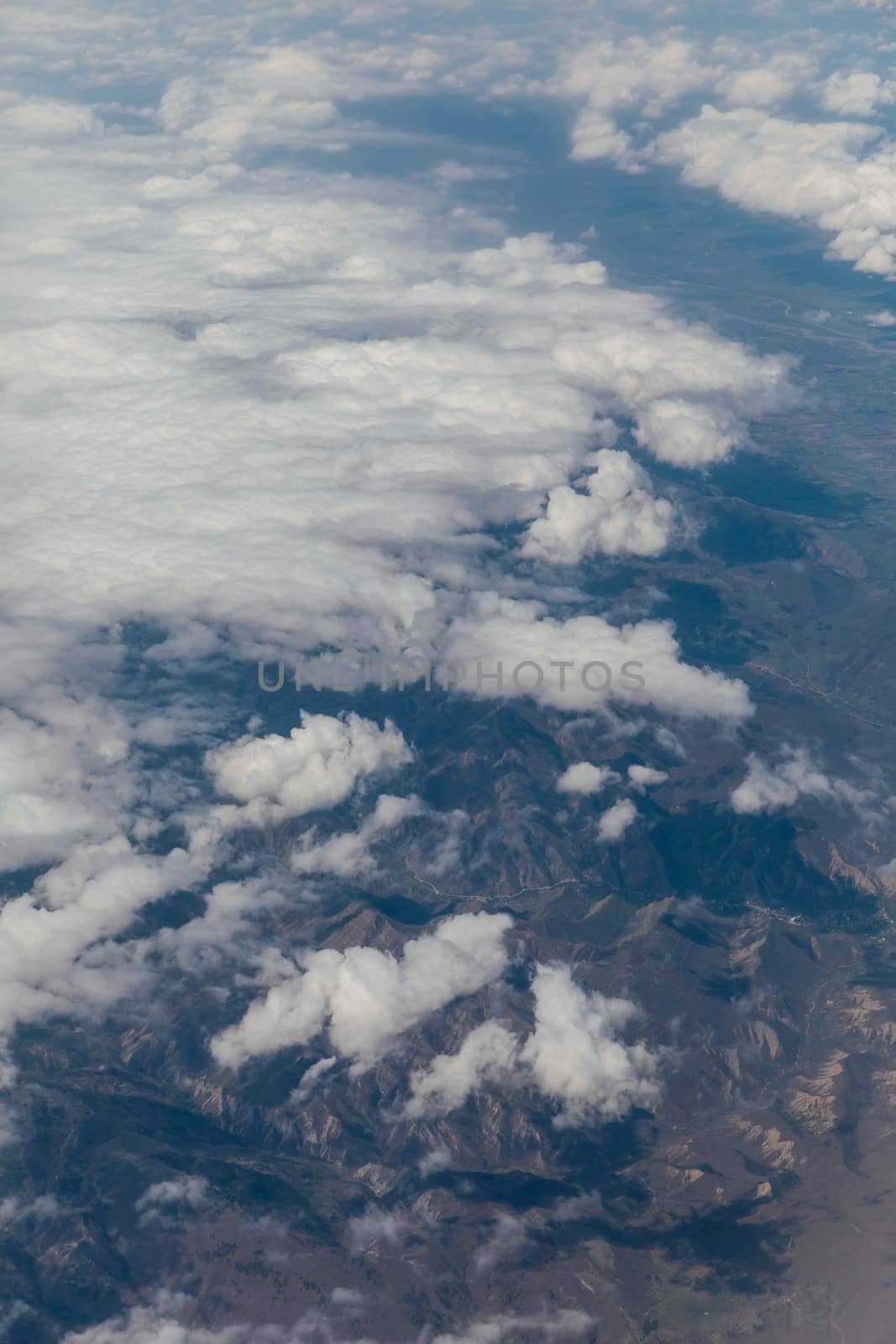 landscape on snowy mountains with clouds from the window of an airplane