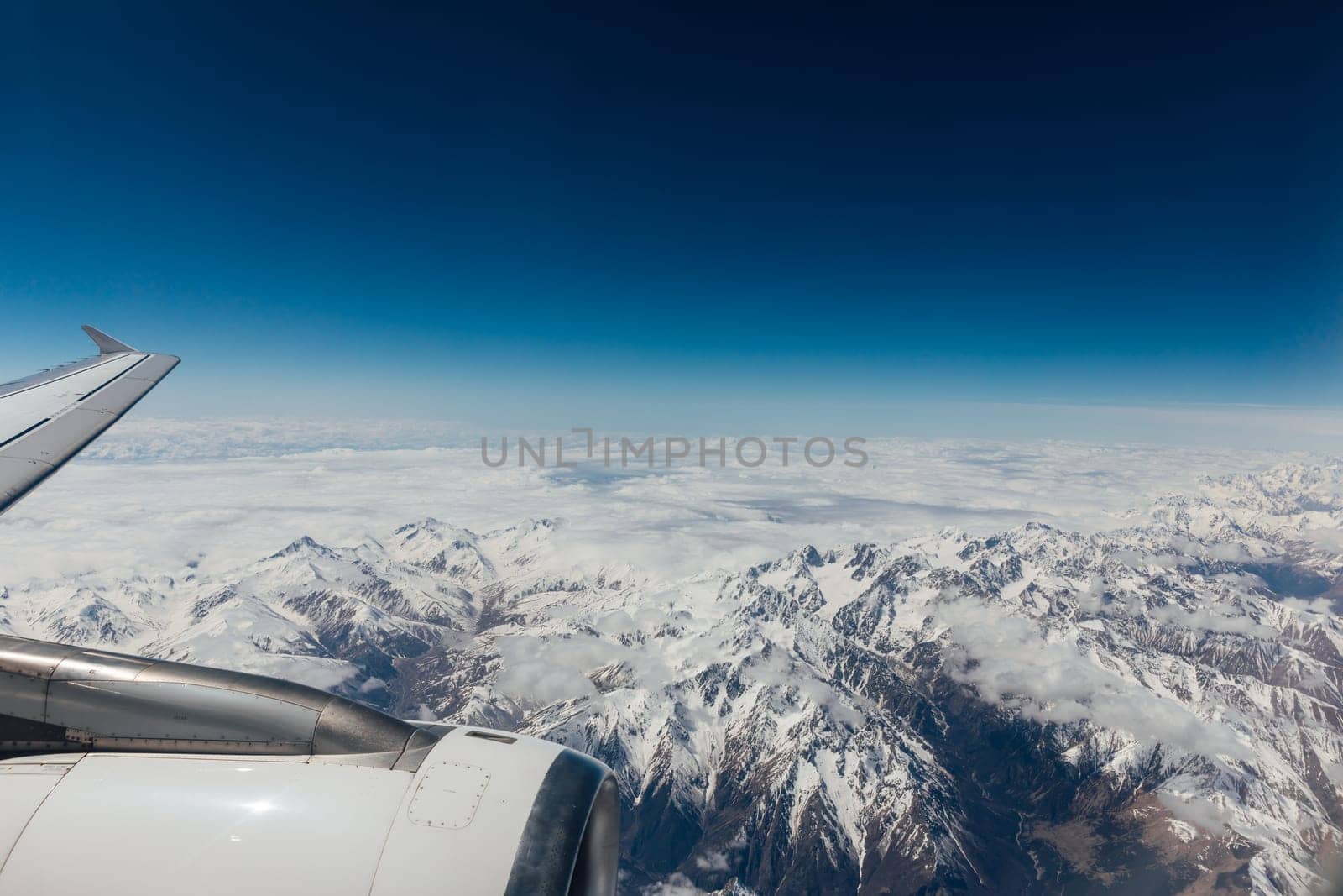 landscape on snowy mountains with clouds from the window of an airplane