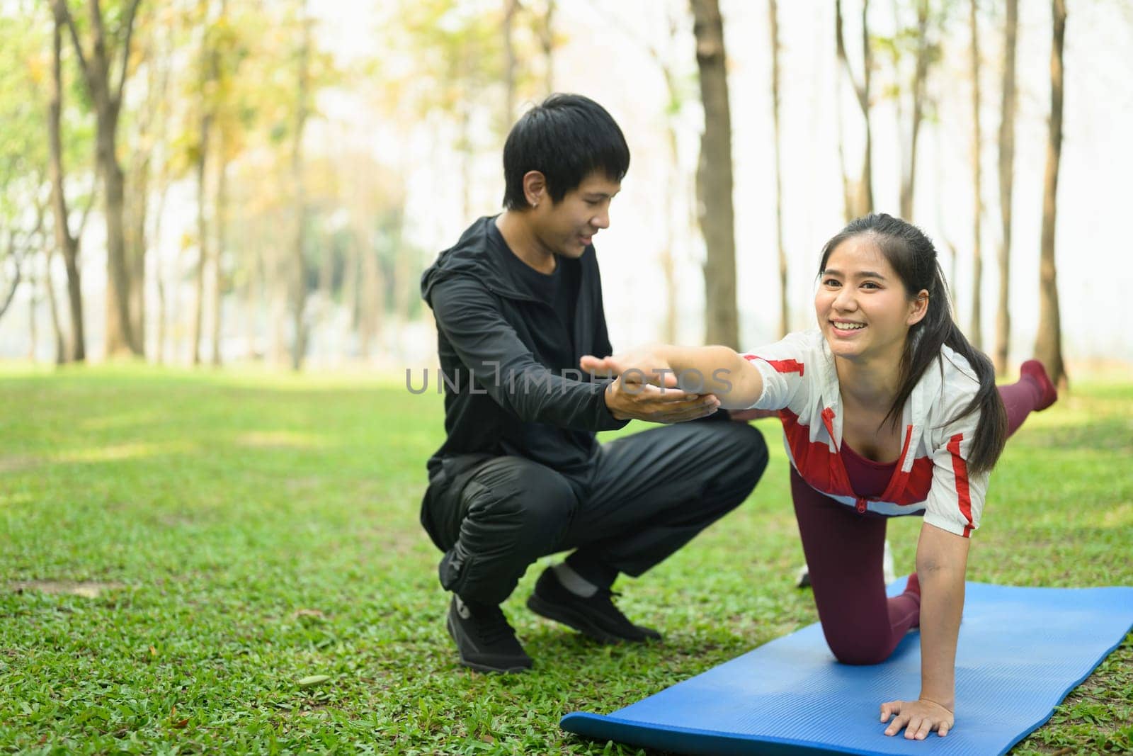 Active young couple practicing yoga together outdoors.