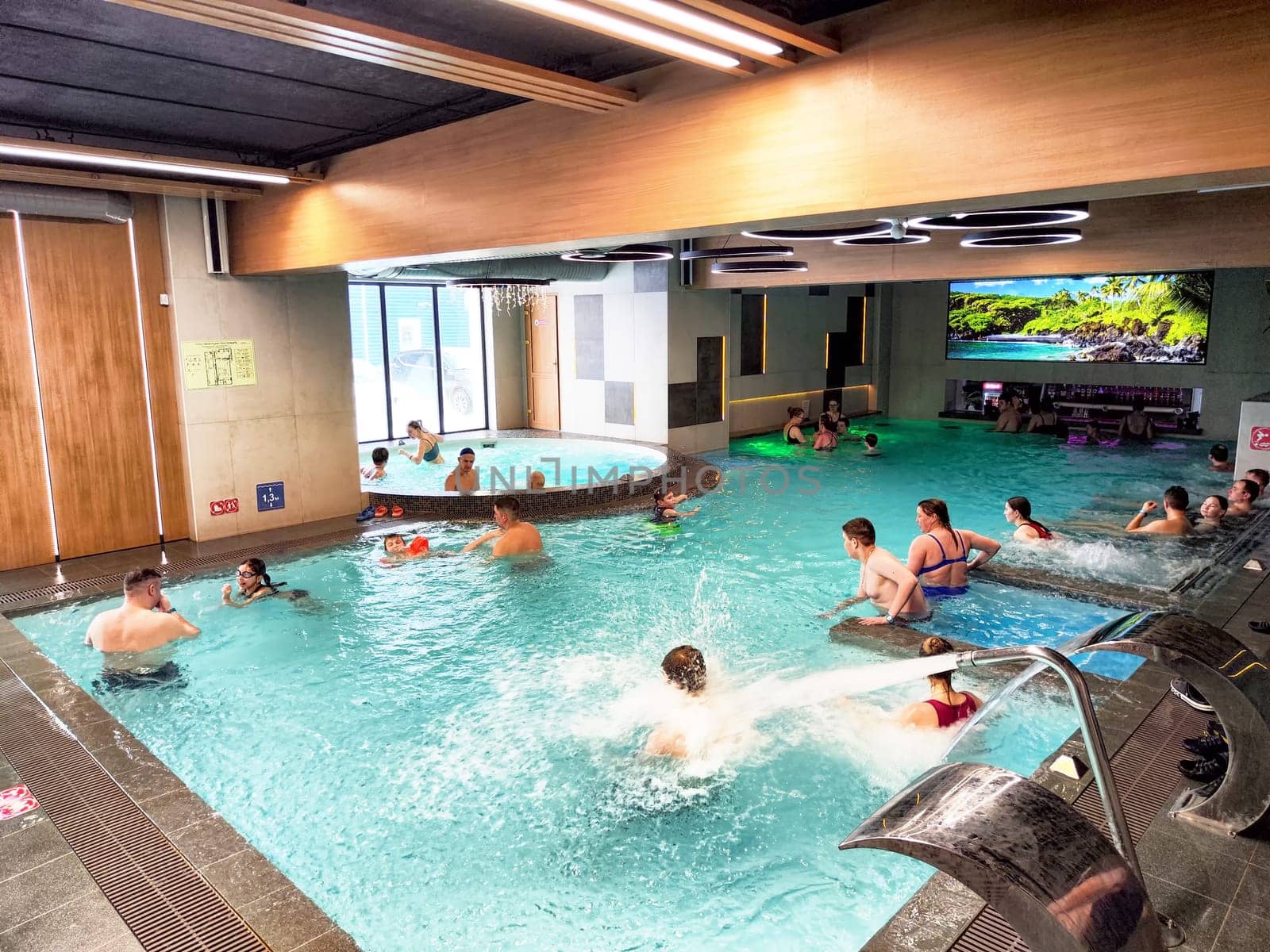 Glazov, Russia - February 16, 2025: Families and children play and relax in the indoor pool at a water park in Glazov, enjoying warm water and vibrant surroundings.