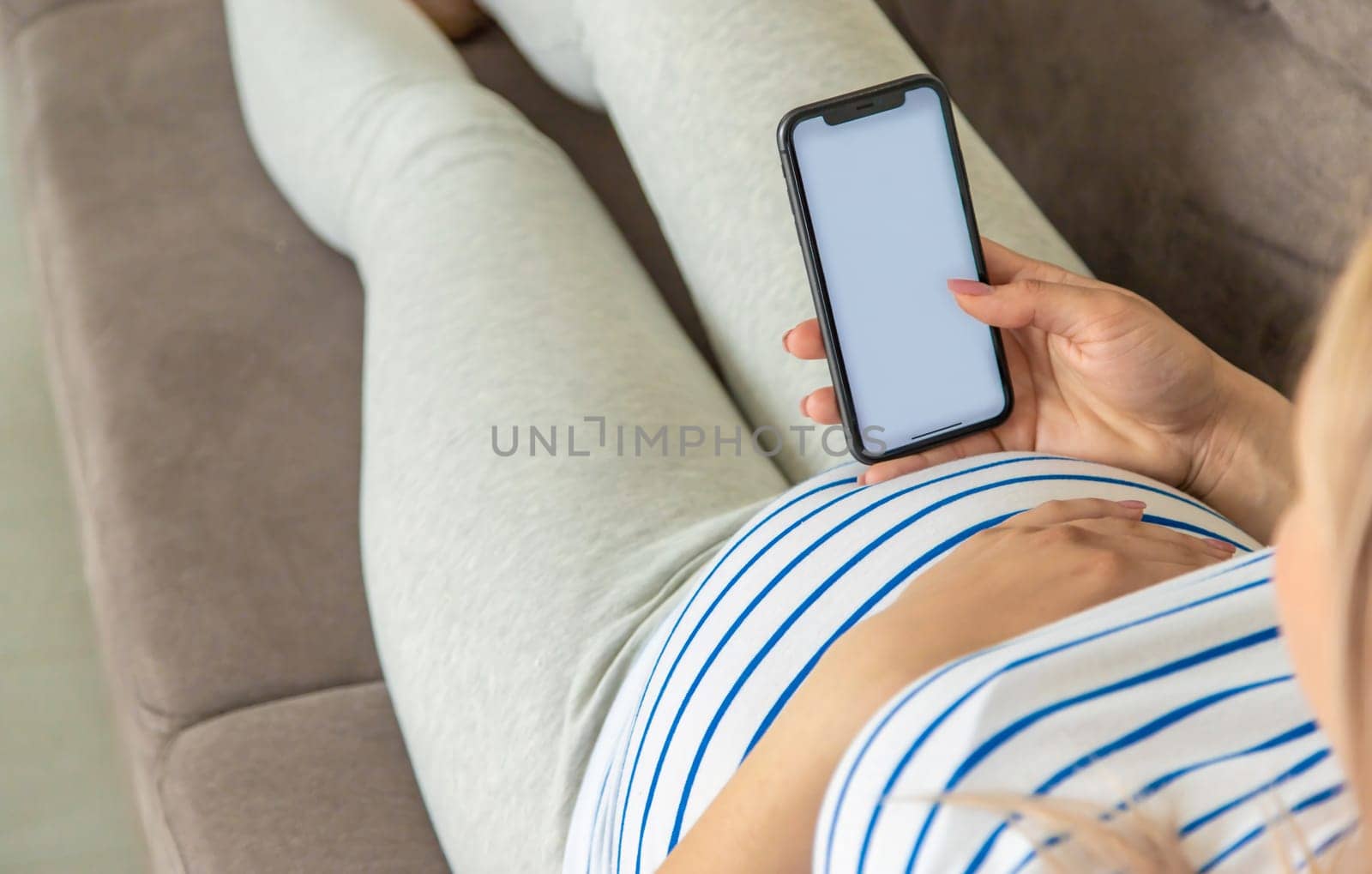 Pregnant woman on the phone in the online store for baby clothing. Selective focus. Cute.