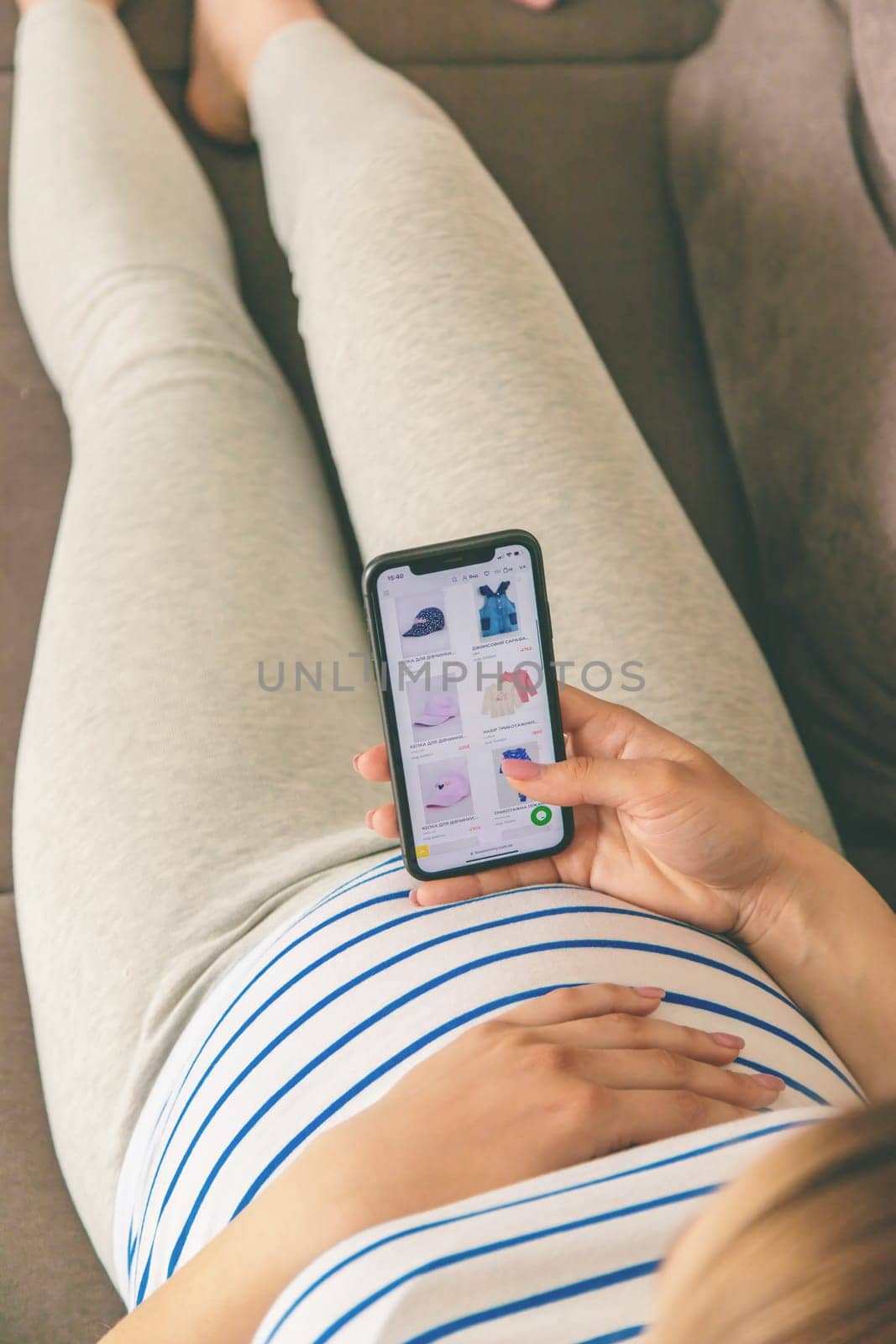 Pregnant woman on the phone in the online store for baby clothing. Selective focus. Cute.