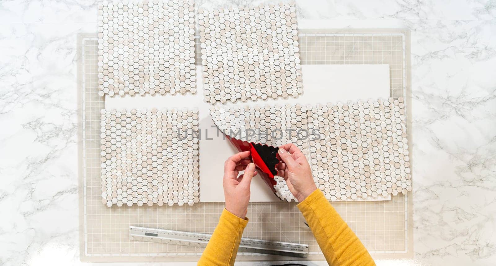 In the process of mounting peel and stick mosaic tiles onto a foam board, perfect for enhancing a food photography studio's aesthetic.