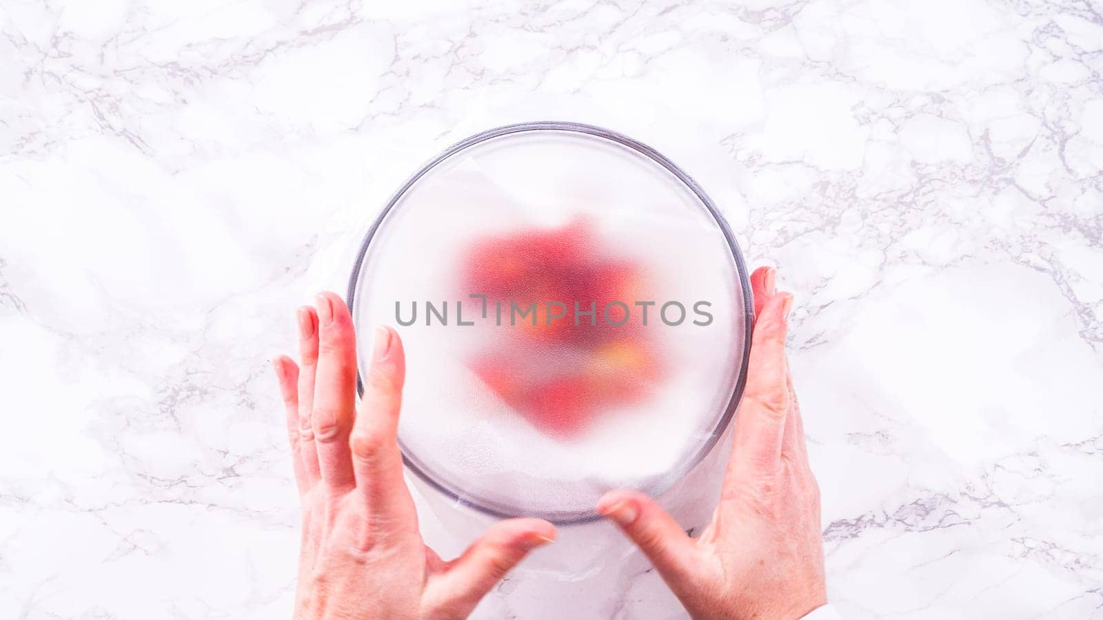 Flat lay. Strawberries, freshly washed and dried, are neatly stored in a glass bowl lined with a paper towel and securely covered with plastic wrap to maintain freshness.