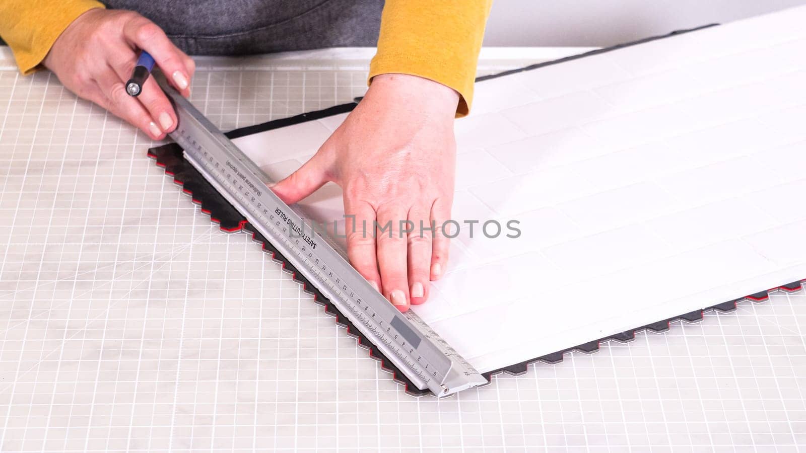 In the process of mounting peel and stick mosaic tiles onto a foam board, perfect for enhancing a food photography studio's aesthetic.