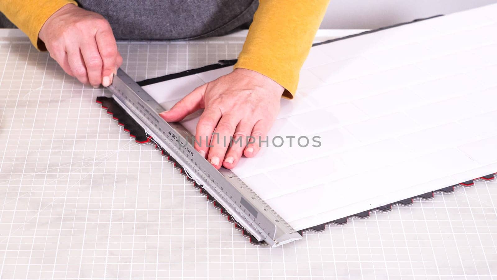 In the process of mounting peel and stick mosaic tiles onto a foam board, perfect for enhancing a food photography studio's aesthetic.