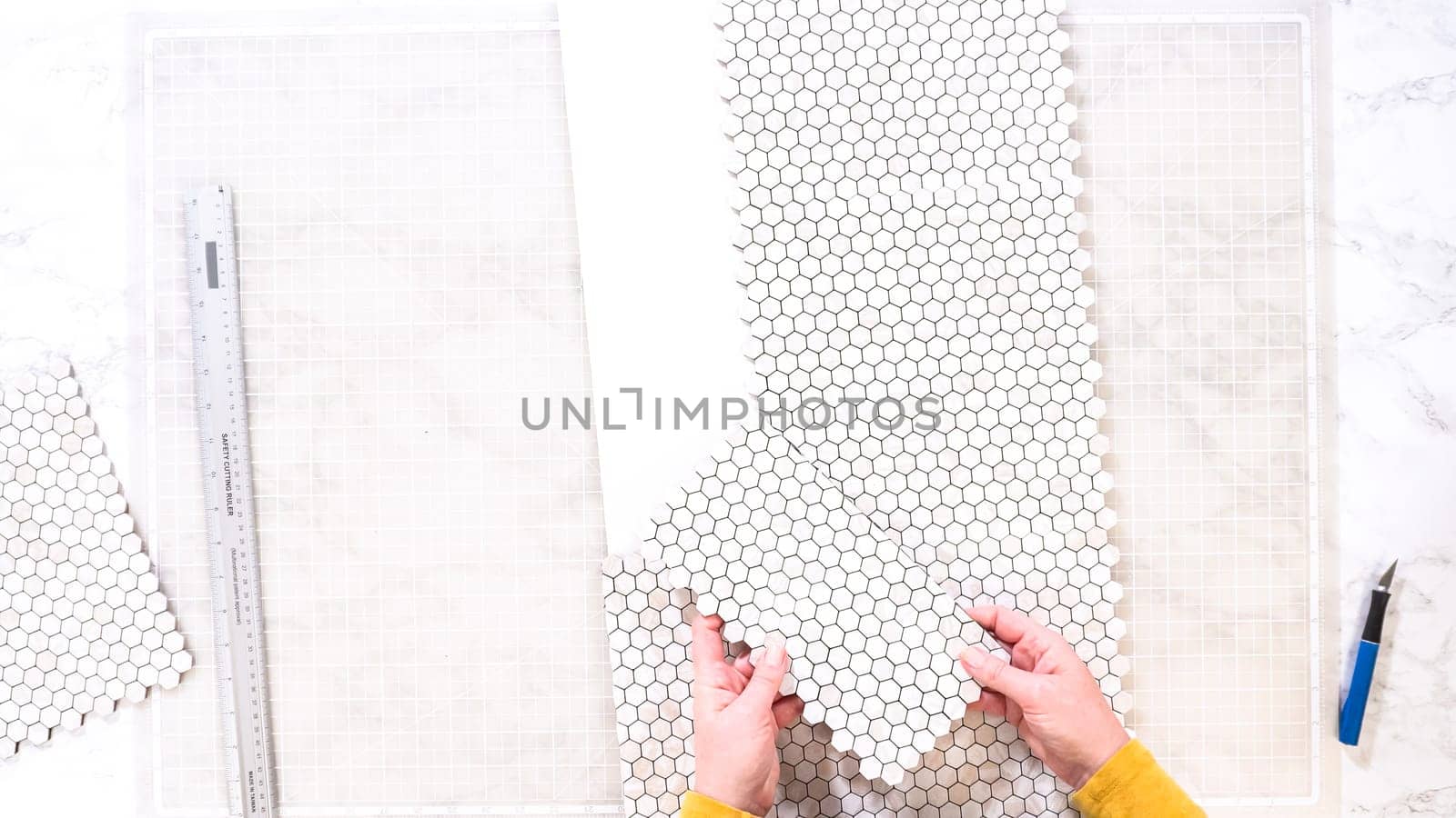 Flat lay. In the process of mounting peel and stick mosaic tiles onto a foam board, perfect for enhancing a food photography studio's aesthetic.