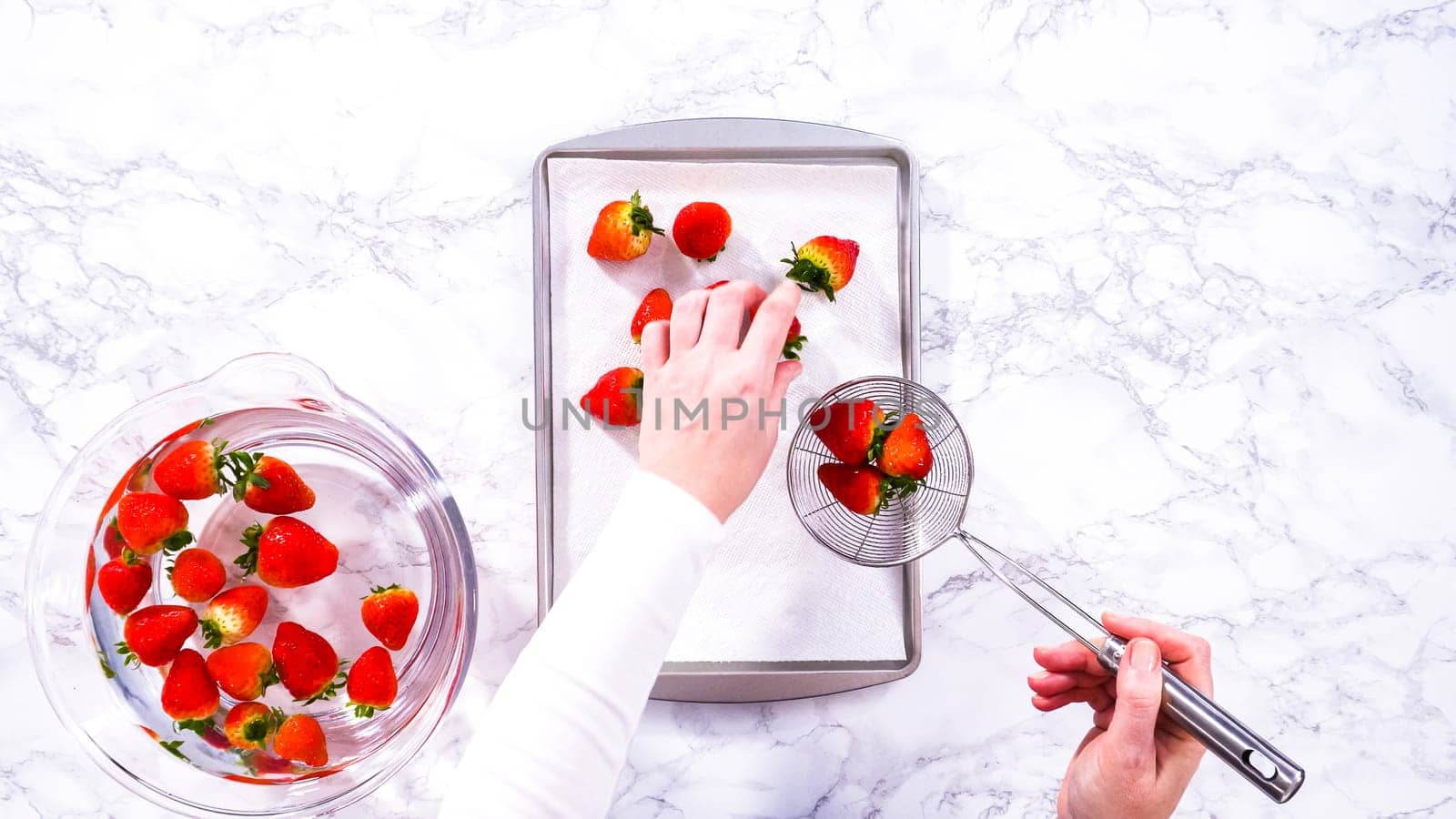Flat lay. Juicy red strawberries, freshly washed, are spread out to dry on a baking sheet, carefully lined with paper towels to absorb excess moisture and prevent mold.