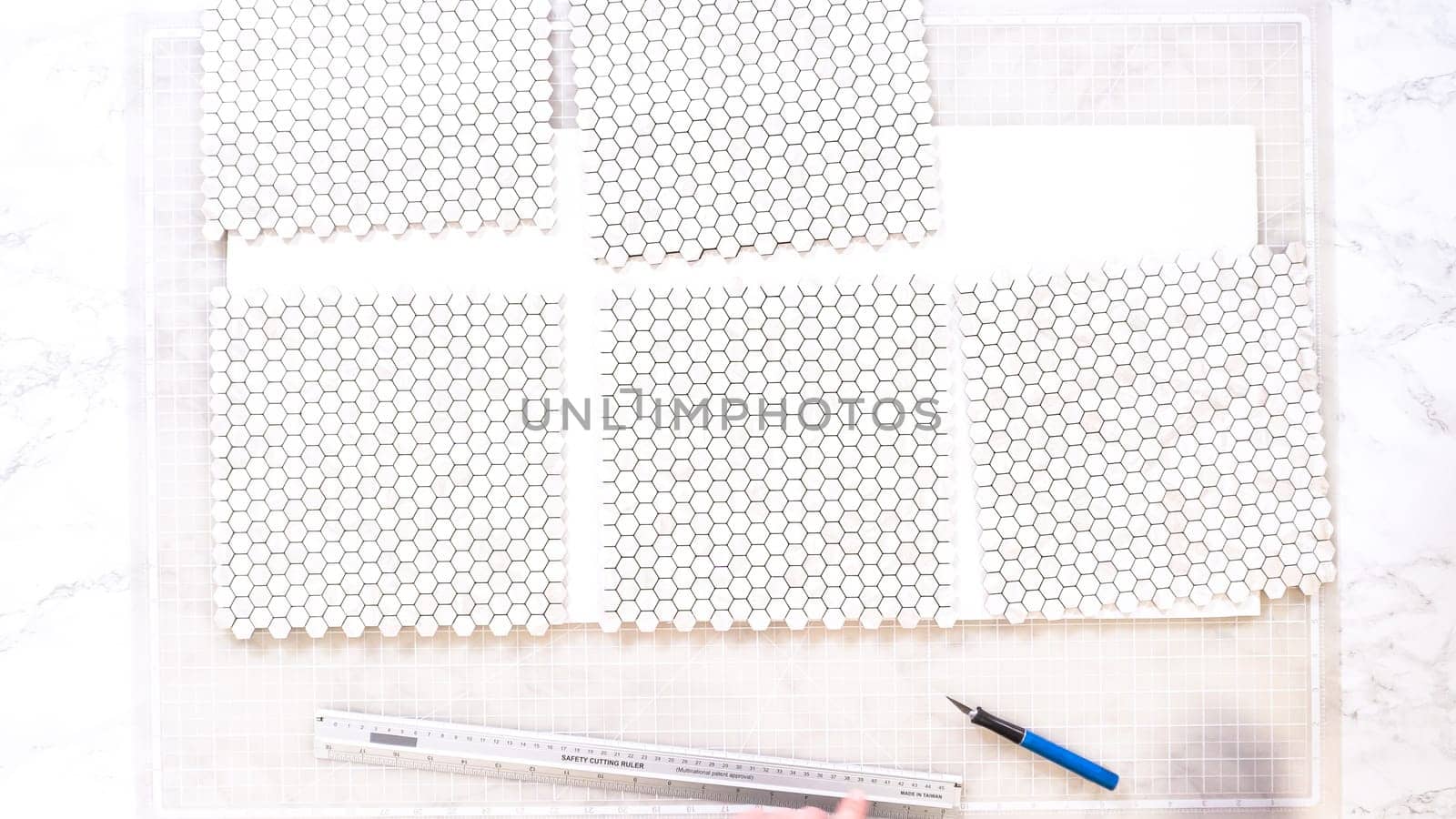 Flat lay. In the process of mounting peel and stick mosaic tiles onto a foam board, perfect for enhancing a food photography studio's aesthetic.