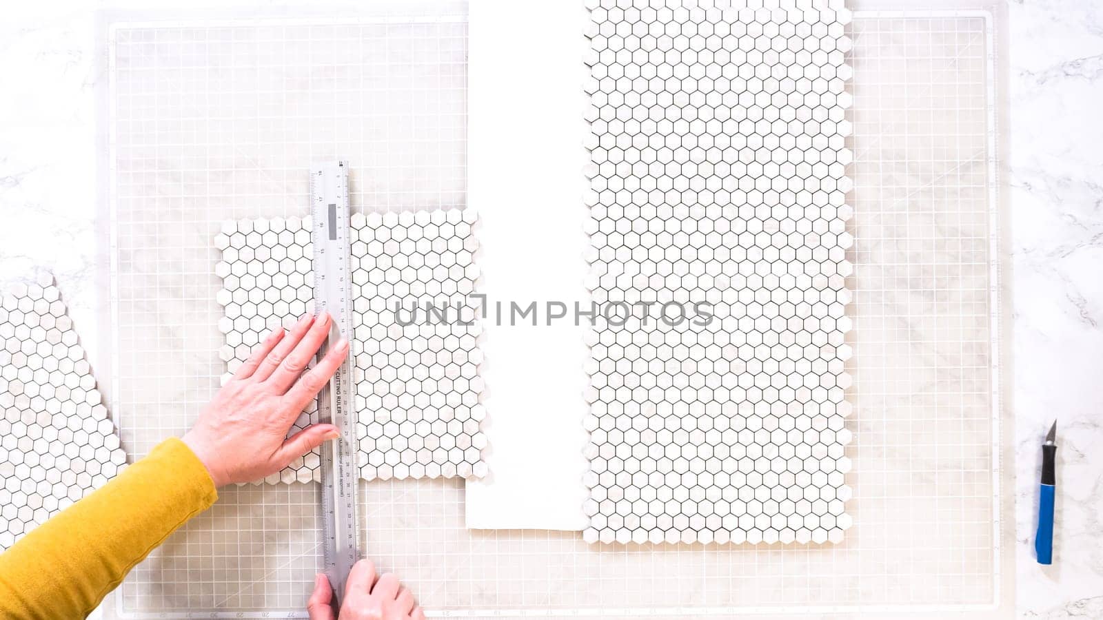 Flat lay. In the process of mounting peel and stick mosaic tiles onto a foam board, perfect for enhancing a food photography studio's aesthetic.