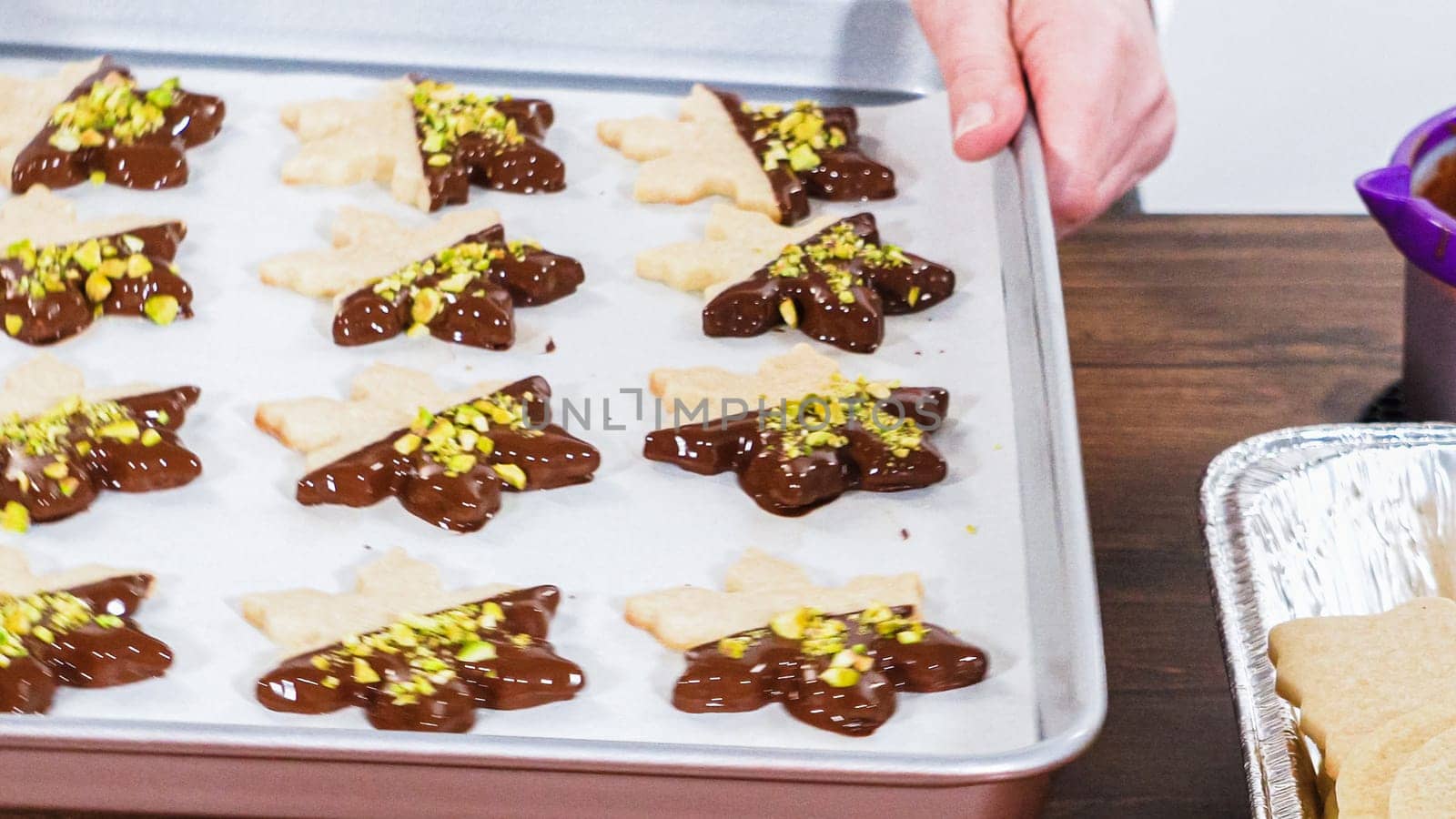 Crafting star-shaped holiday cookies dipped in chocolate and sprinkled with variety of toppings.