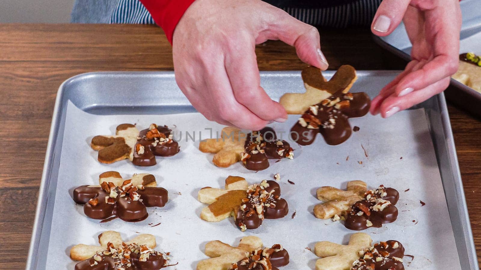 Carefully packaging Christmas cutout cookies, half-dipped in chocolate and presented in clear cellophane wrapping, perfect for festive gifting.