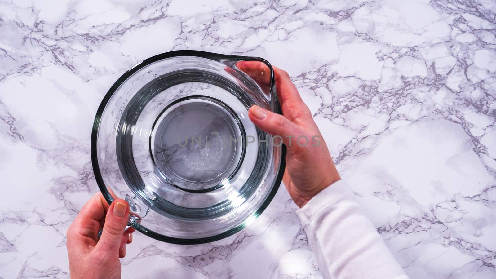 Flat lay. A spacious glass mixing bowl filled with water sits prepared to gently cleanse a batch of ripe strawberries, ensuring they are pristine before drying or storage.