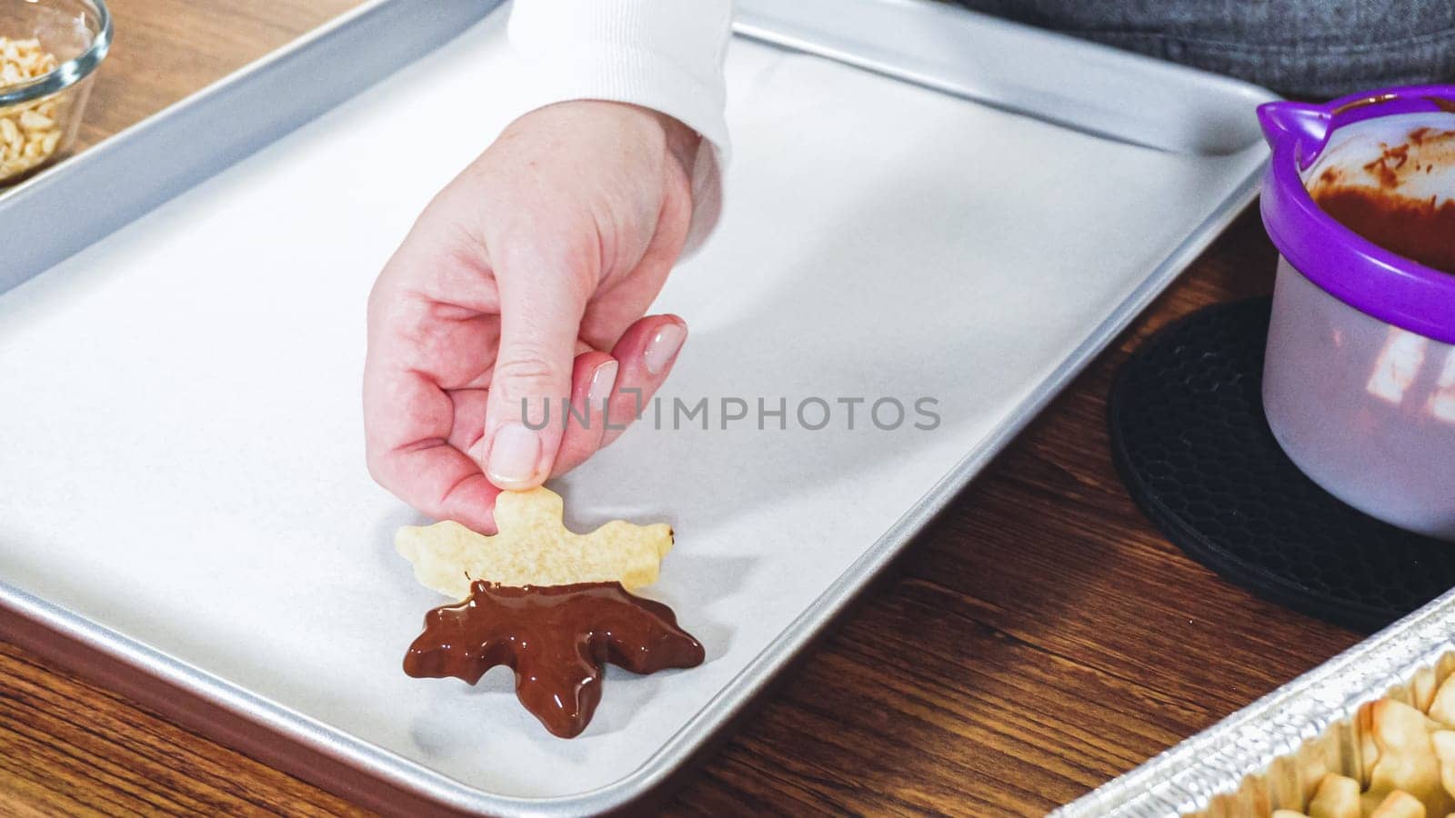 Crafting star-shaped holiday cookies dipped in chocolate and sprinkled with variety of toppings.