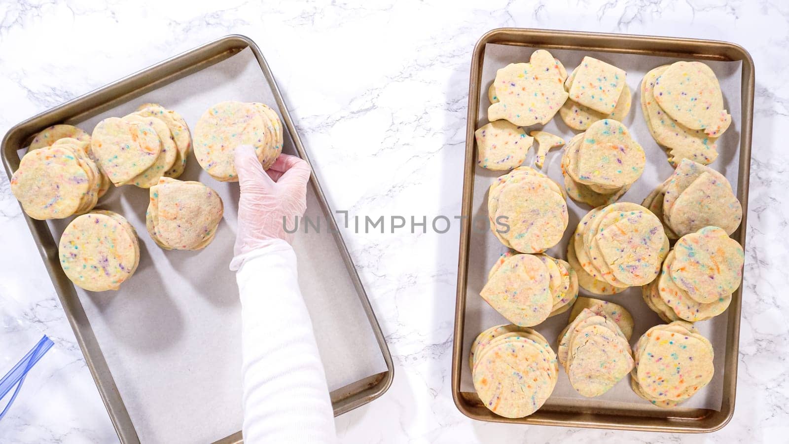 Flat lay. With precision, the woman is carefully arranging the sugar cookies, filled with dough-mixed sprinkles, into a rustic brown paper box.