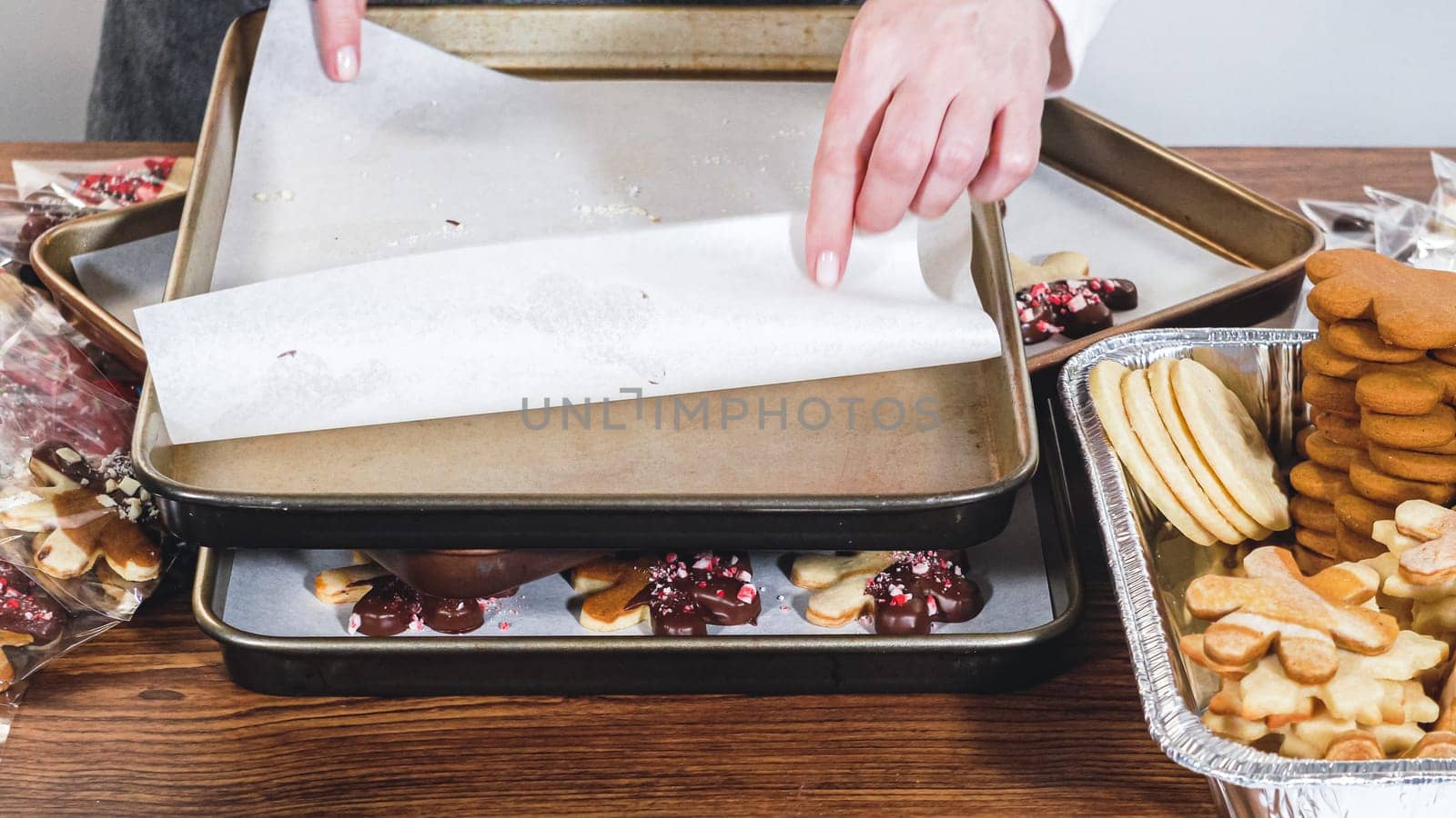 Carefully packaging Christmas cutout cookies, half-dipped in chocolate and presented in clear cellophane wrapping, perfect for festive gifting.