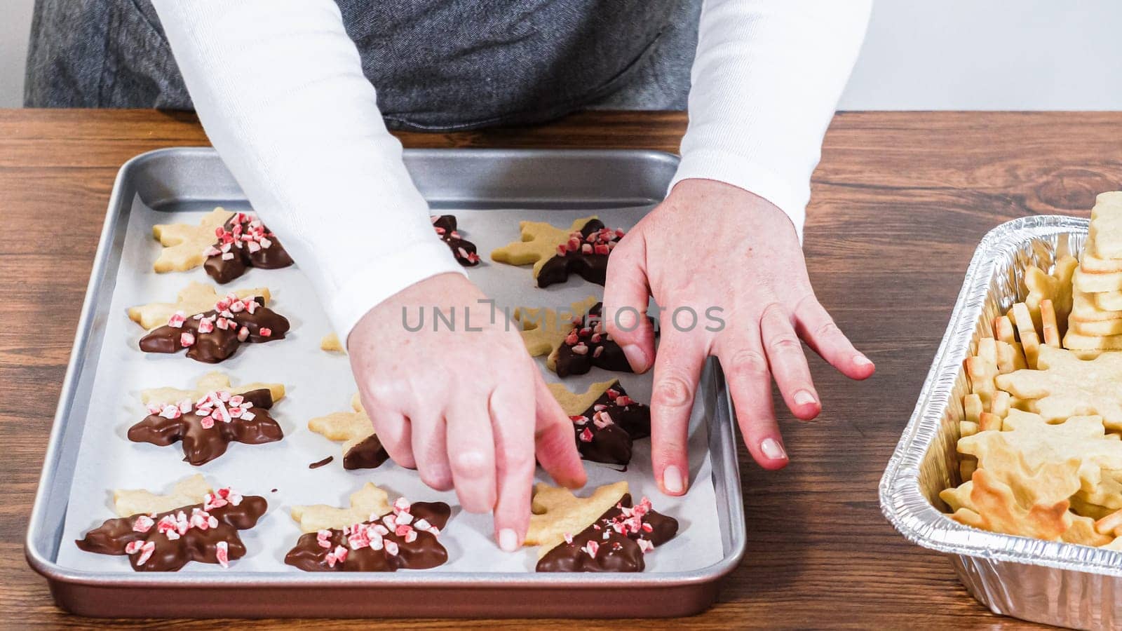 Carefully packaging Christmas cutout cookies, half-dipped in chocolate and presented in clear cellophane wrapping, perfect for festive gifting.