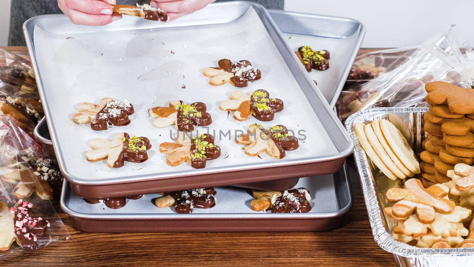 Carefully packaging Christmas cutout cookies, half-dipped in chocolate and presented in clear cellophane wrapping, perfect for festive gifting.