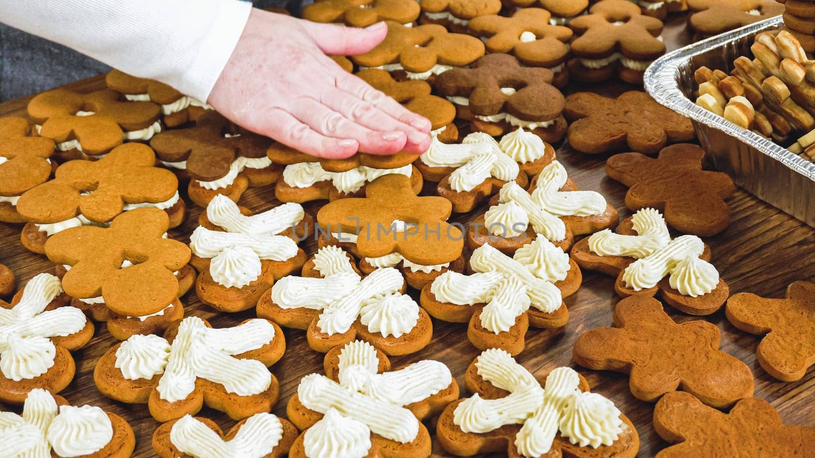 Crafting gingerbread cookie sandwiches with eggnog buttercream, presented on a rustic wooden table for Christmas gifting.