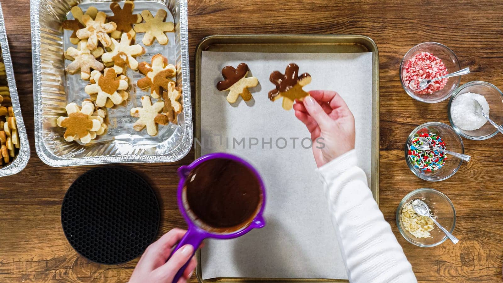 Flat lay. Creating snowflake-shaped cutout sugar cookies, dipped in chocolate, and adorned with different toppings.