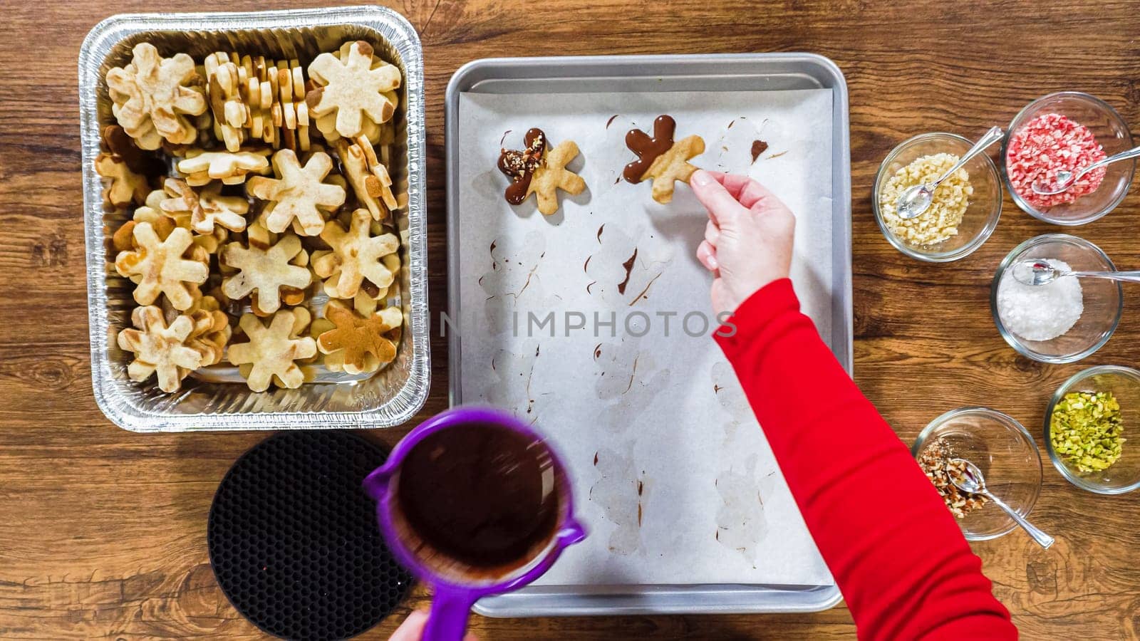 Flat lay. Creating snowflake-shaped cutout sugar cookies, dipped in chocolate, and adorned with different toppings.