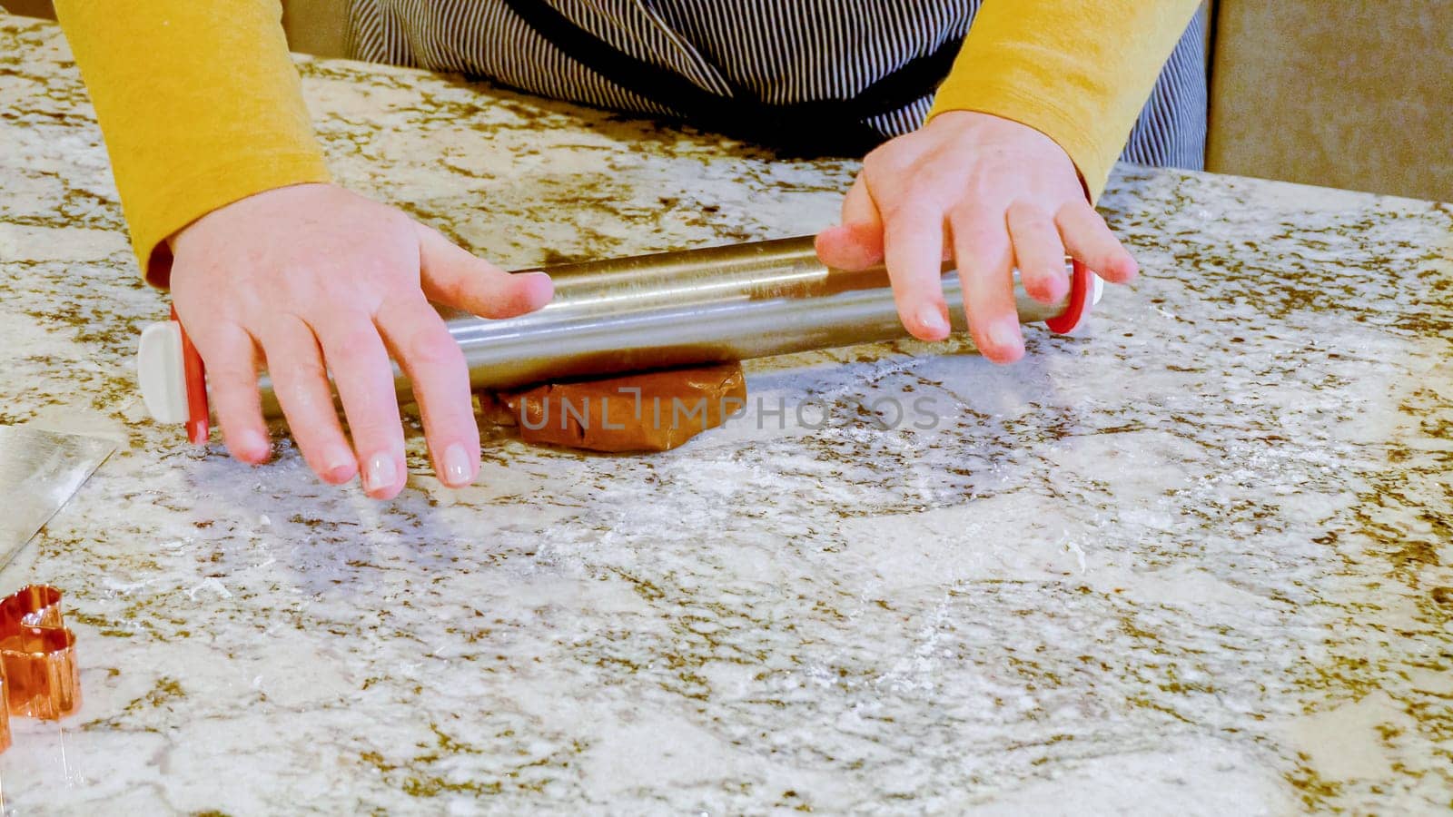 Using an adjustable rolling pin to roll out gingerbread cookie dough on the elegant marble counter in a modern kitchen, getting ready for festive holiday baking.