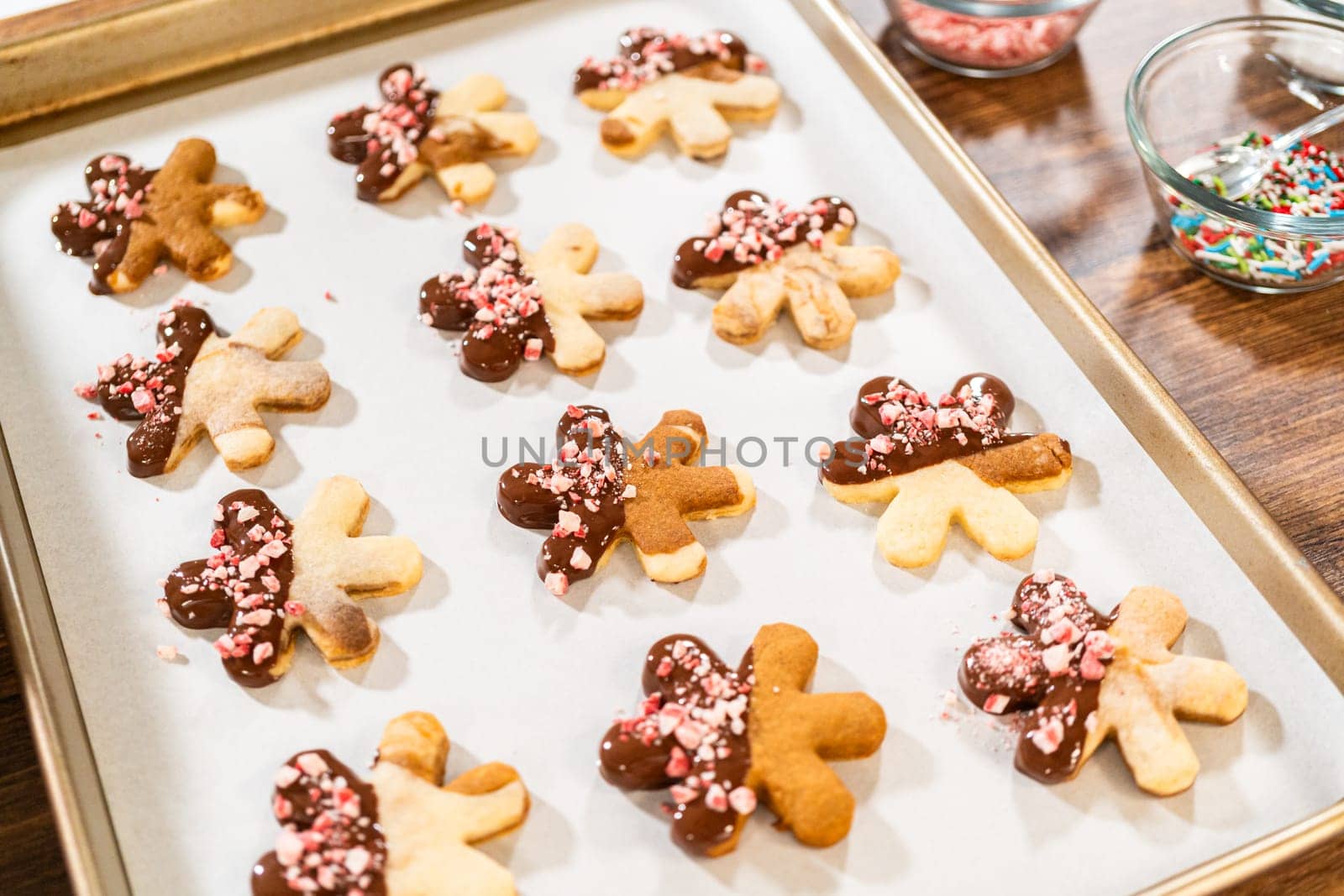 Preparing star-shaped cookies, half-dipped in chocolate, accented with peppermint chocolate chips for the holidays.