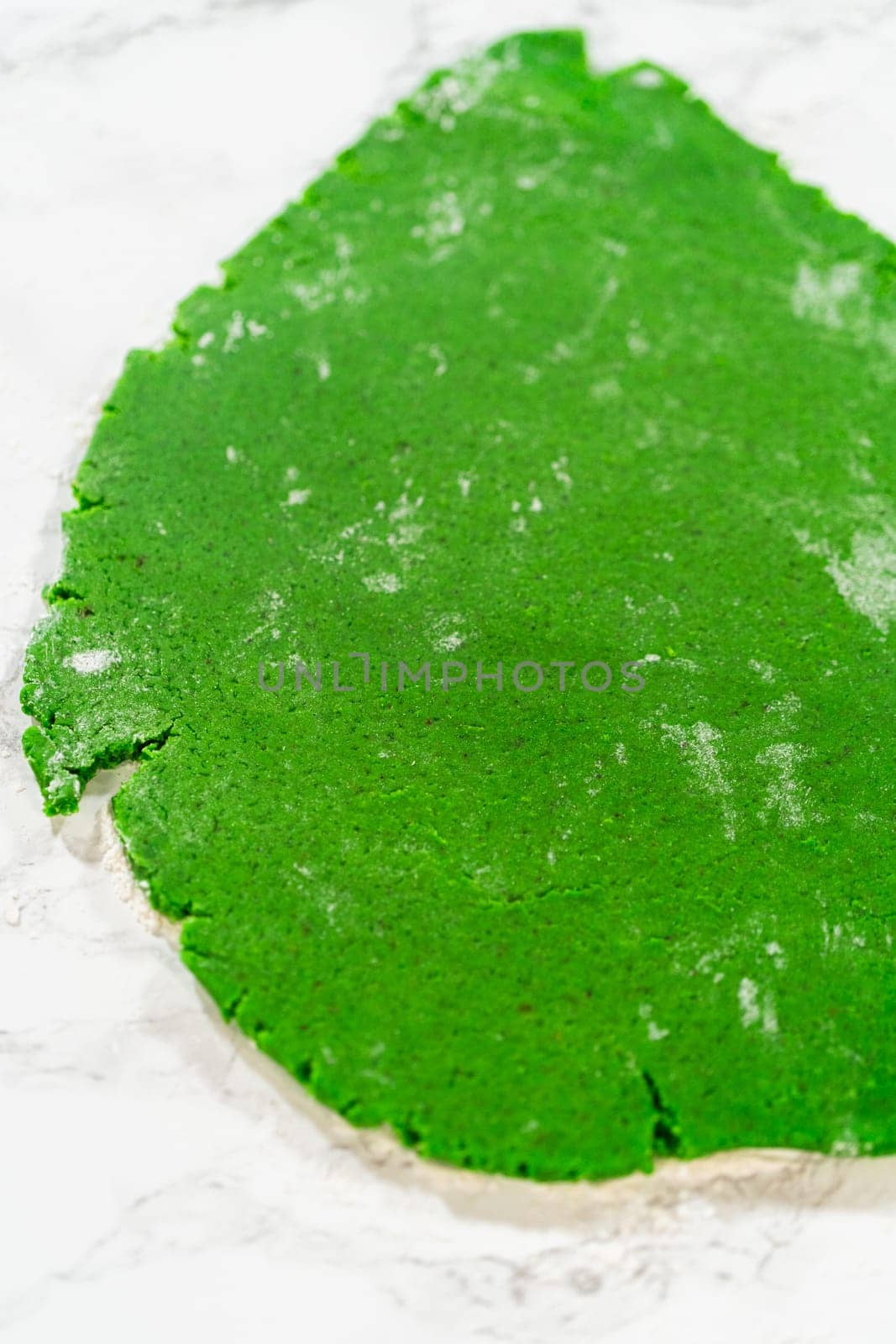 An overhead perspective of smoothly rolled green gingerbread dough spread out on a marble surface, showcasing the vibrant green color of the Green Gingerbread Cookies dough, ready to be shaped.