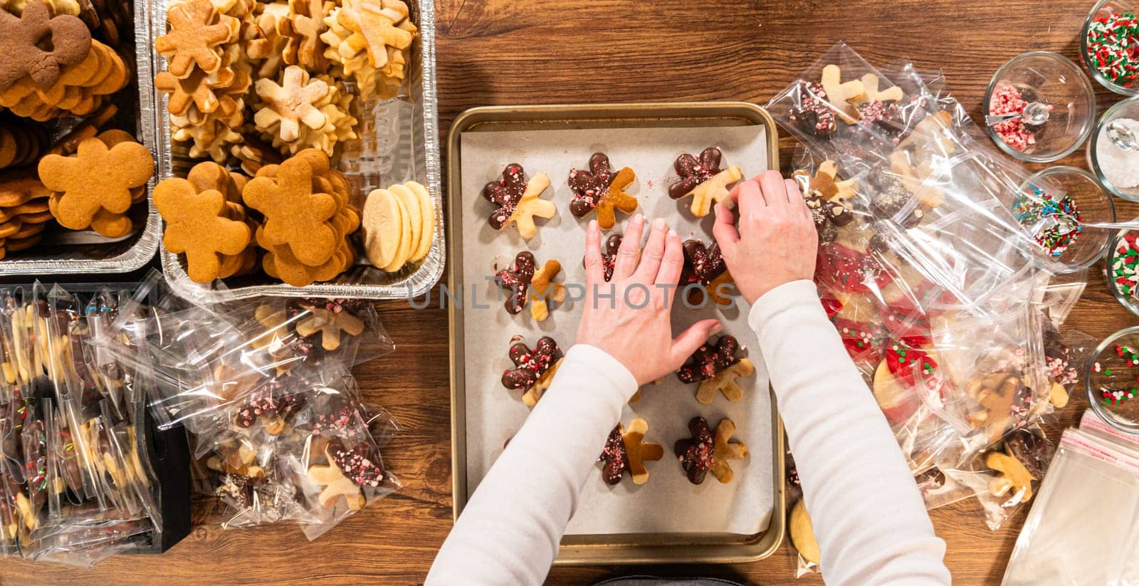Carefully packaging Christmas cutout cookies, half-dipped in chocolate and presented in clear cellophane wrapping, perfect for festive gifting.