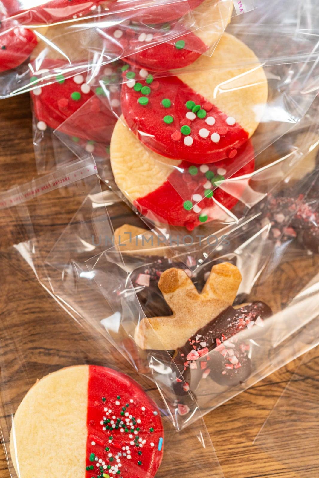 Carefully packaging Christmas cutout cookies, half-dipped in chocolate and presented in clear cellophane wrapping, perfect for festive gifting.
