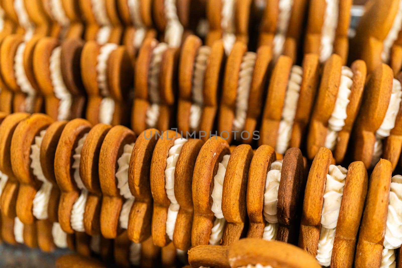 Making gingerbread man cookie sandwiches filled with eggnog buttercream, arrayed on a rustic wooden table, ideal for heartfelt Christmas gifting.