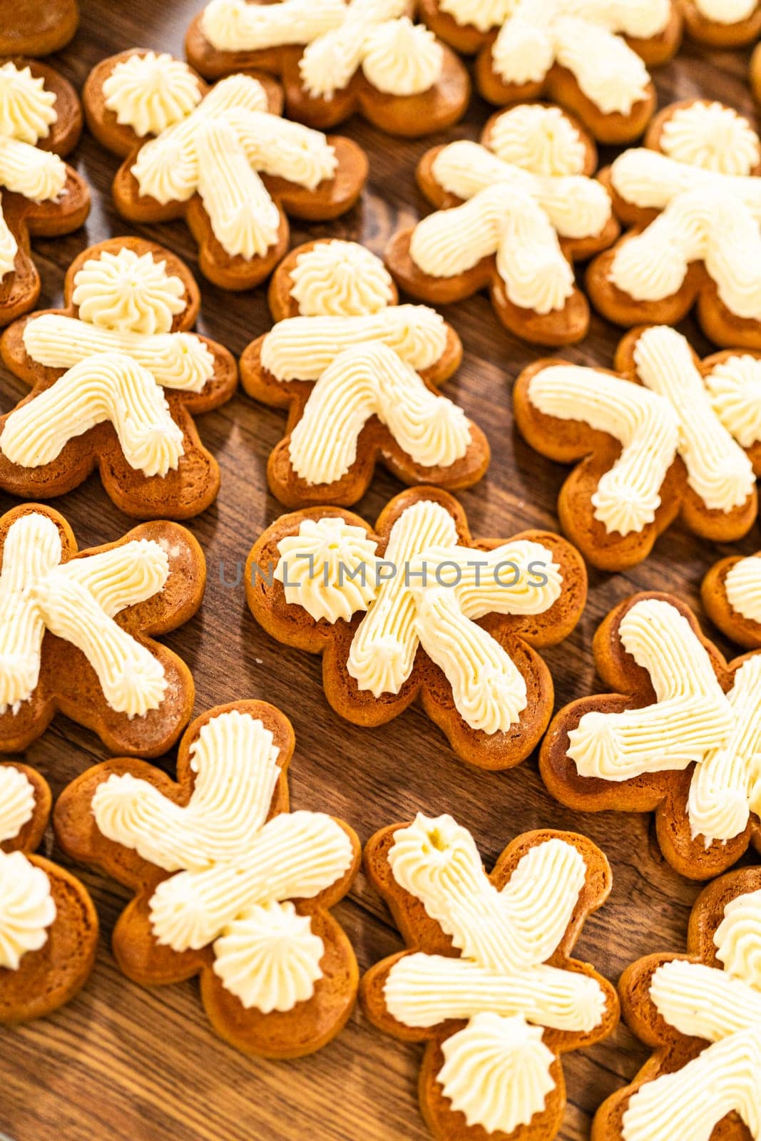 Making gingerbread man cookie sandwiches filled with eggnog buttercream, arrayed on a rustic wooden table, ideal for heartfelt Christmas gifting.