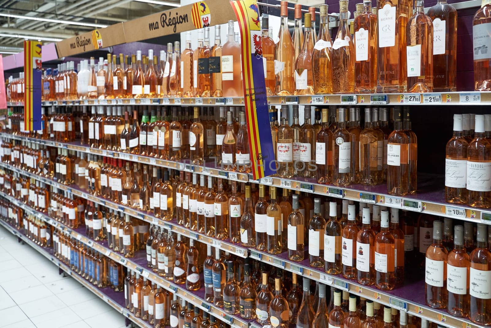 Nice, France - June 13, 2023: Lots of local traditional rose wine bottles on a shelf of a local store