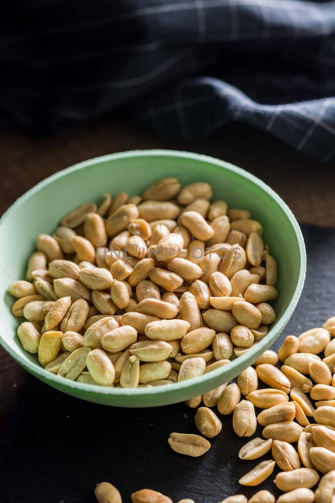 Roasted salted peanuts in bowl on a wooden table.