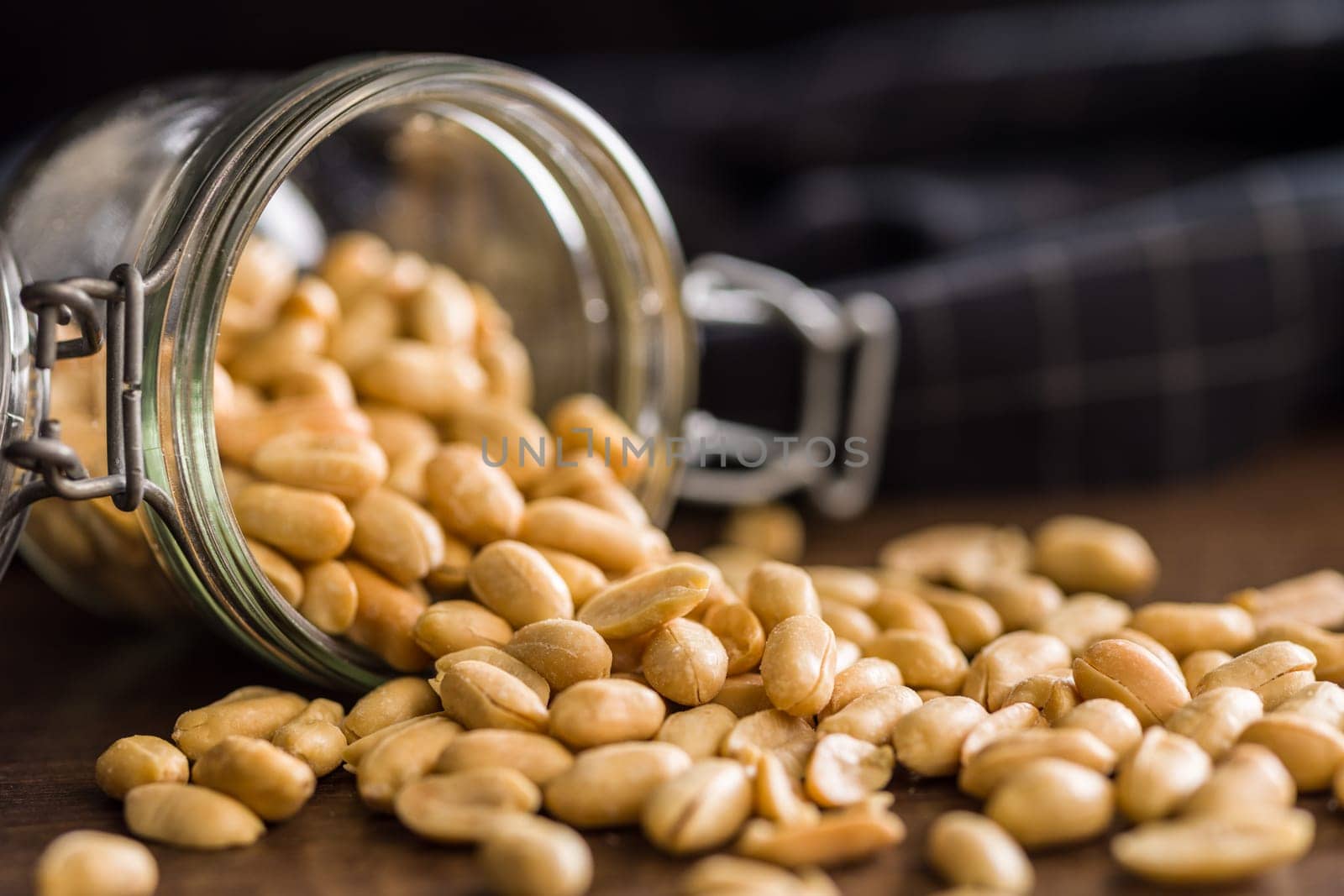 Roasted salted peanuts in jar on a wooden table.