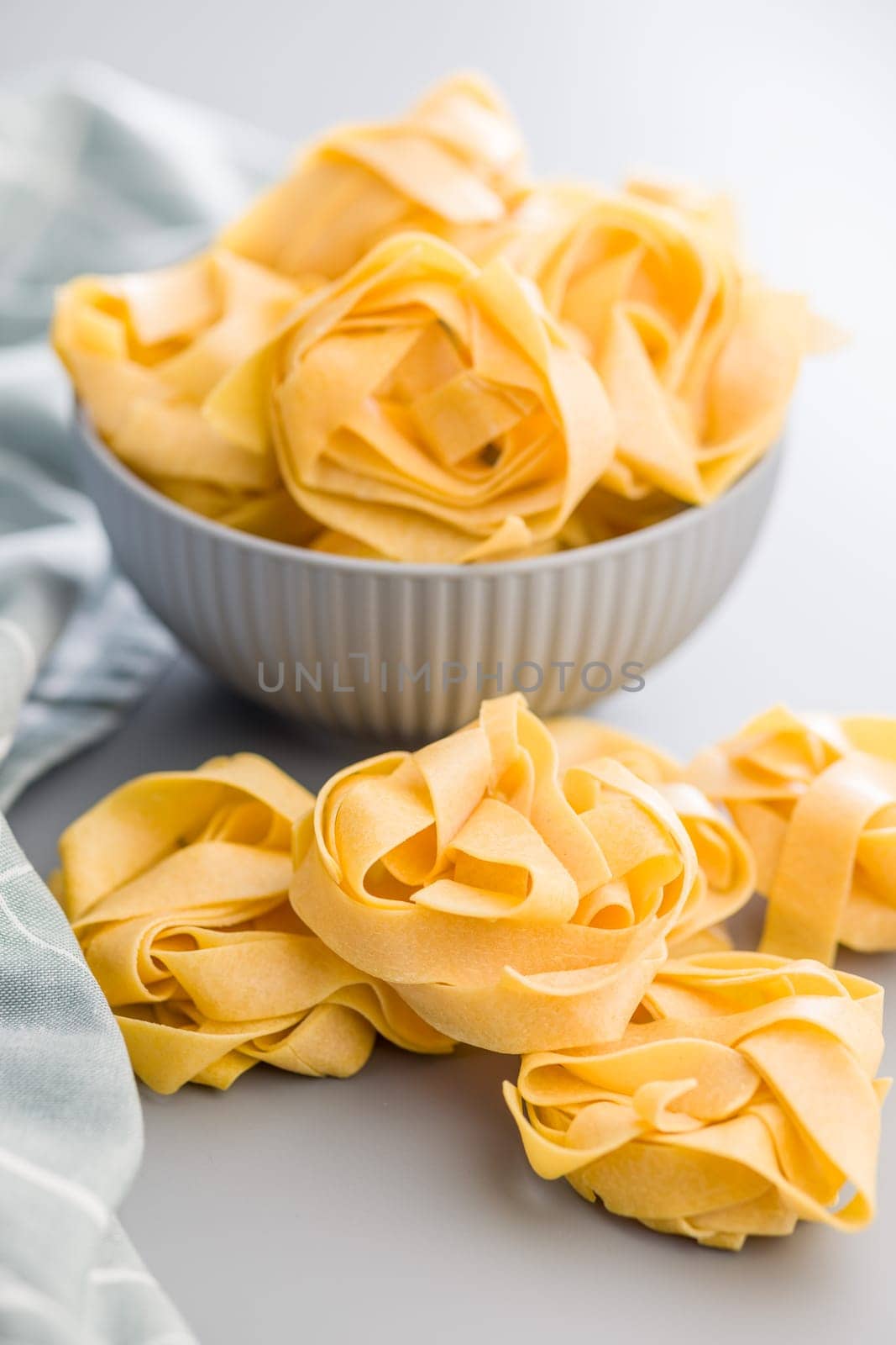 Italian pasta tagliatelle. Uncooked noodle pasta on a gray background.