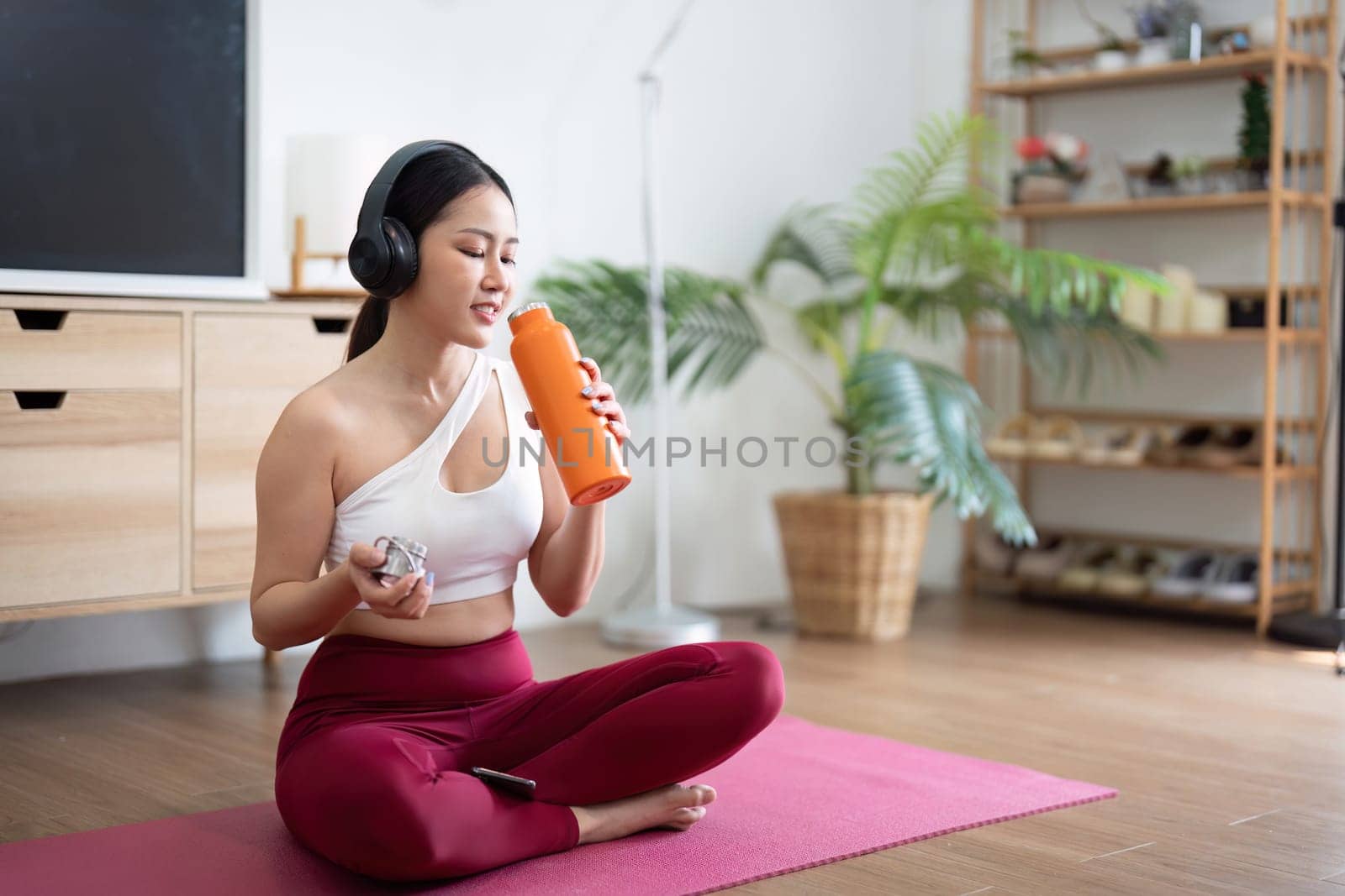 After a productive yoga session, a woman hydrates with her water bottle, emphasizing the importance of wellness and self-care.
