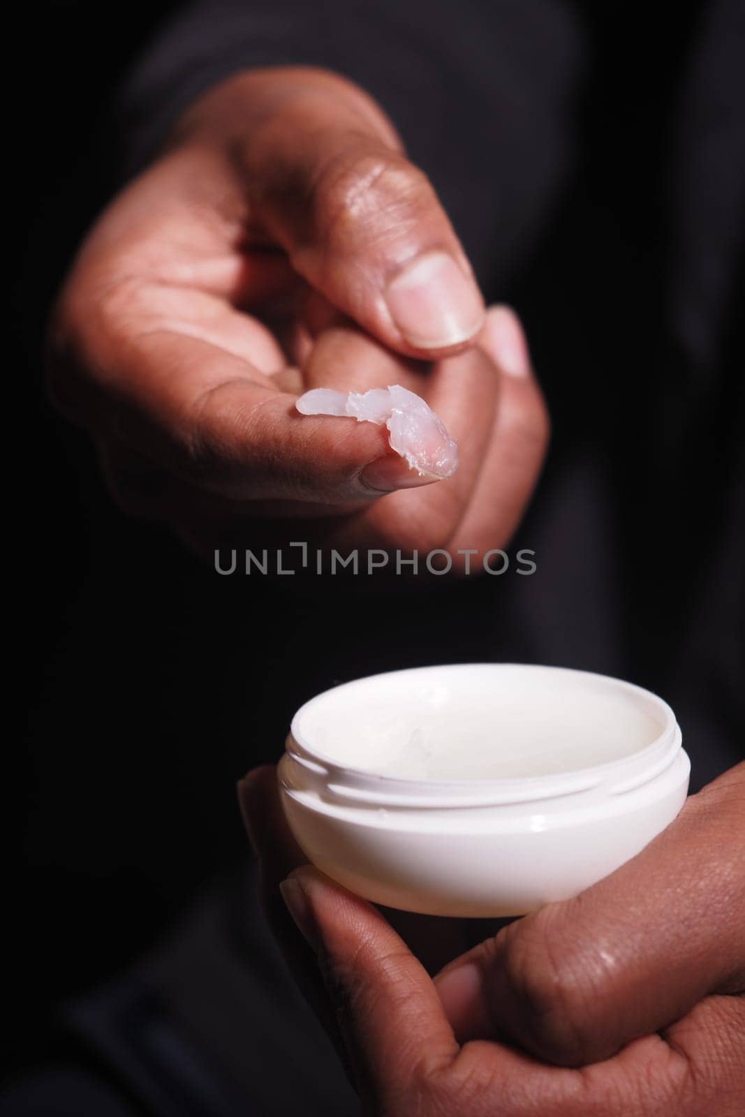 Hands applying petroleum jelly closeup .