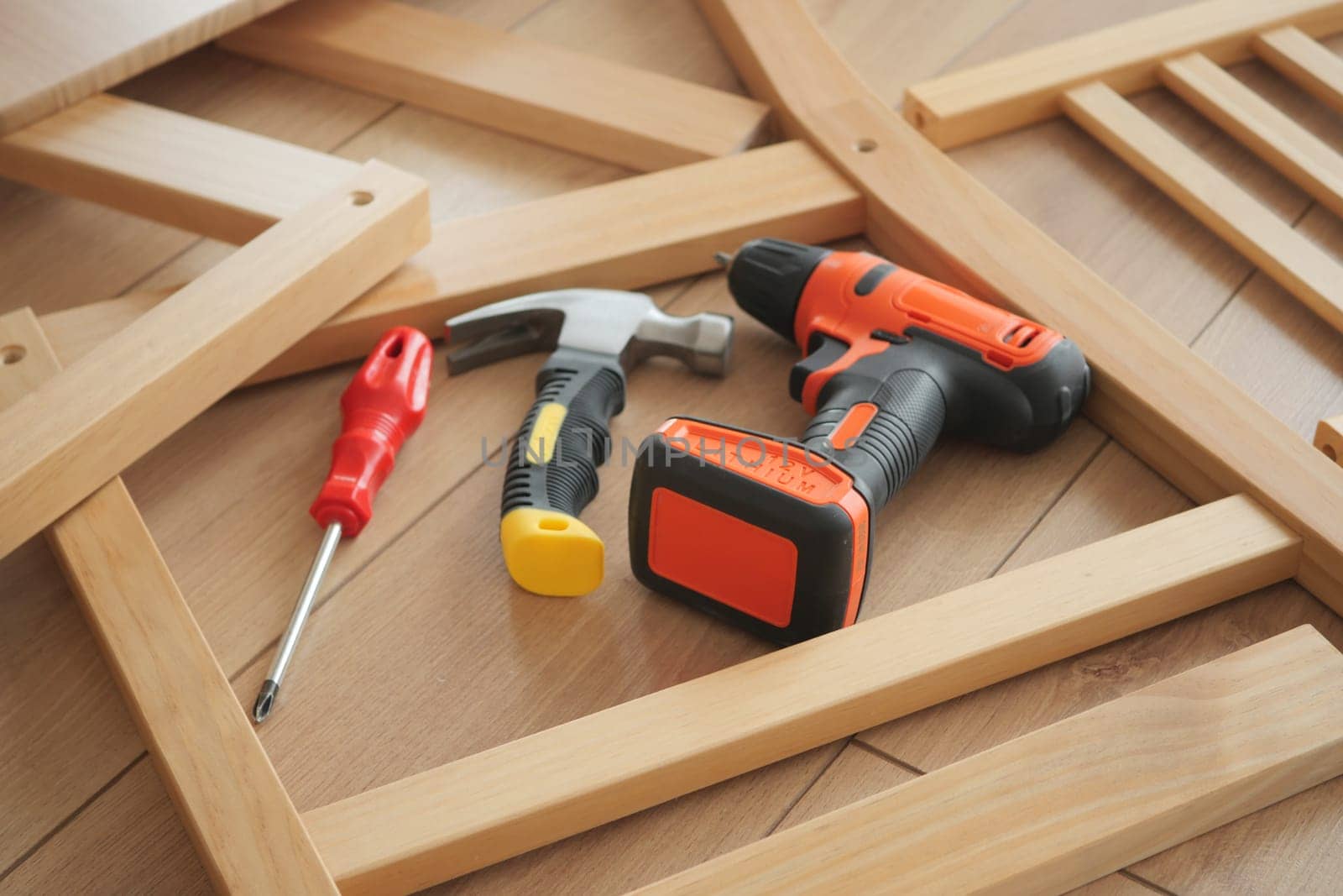 Various tools are laid out for assembling furniture on a wooden surface.